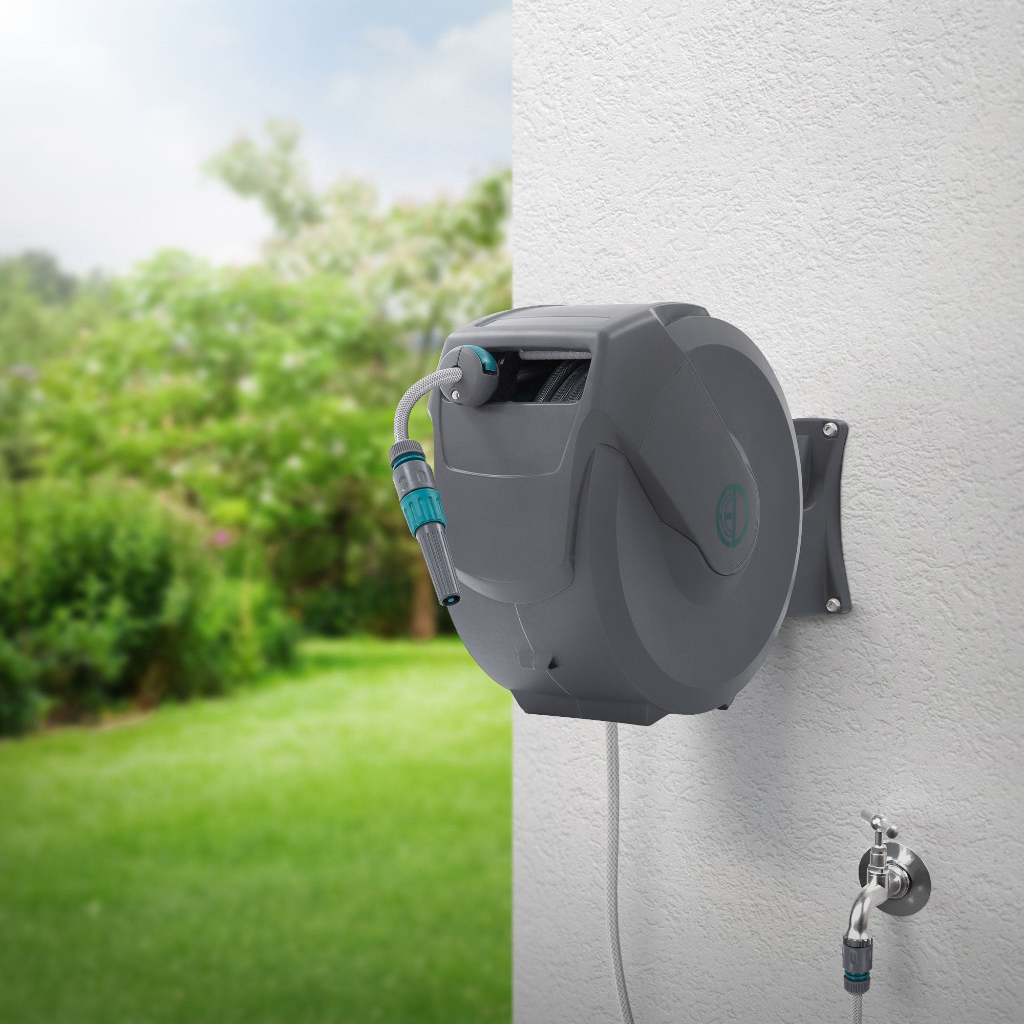 Wasserrolle mit Schlauch, an einer Wand montiert, im Freien mit grünem Garten.