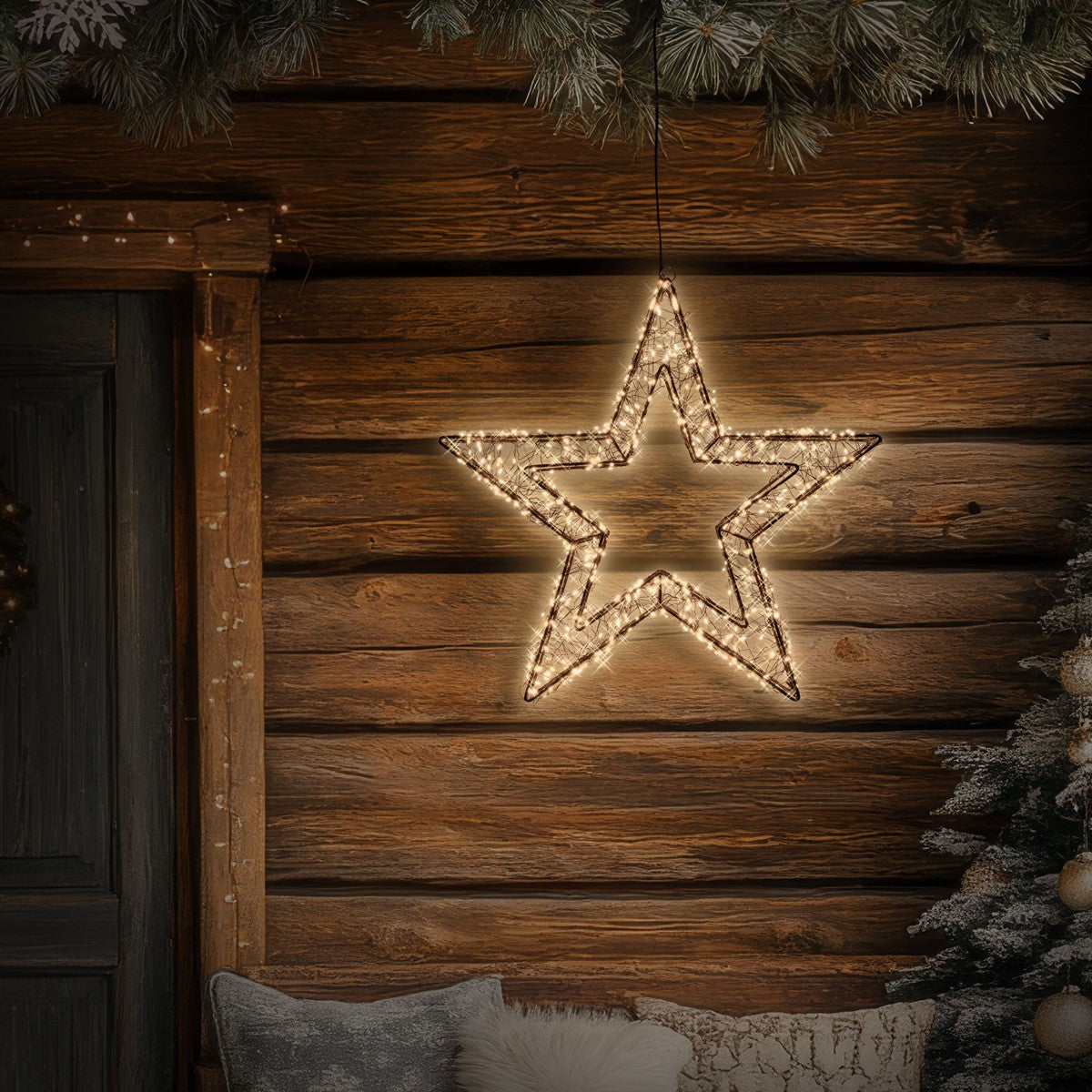 Una estrella luminosa cuelga delante de un revestimiento de madera, rodeada de ramas de abeto.