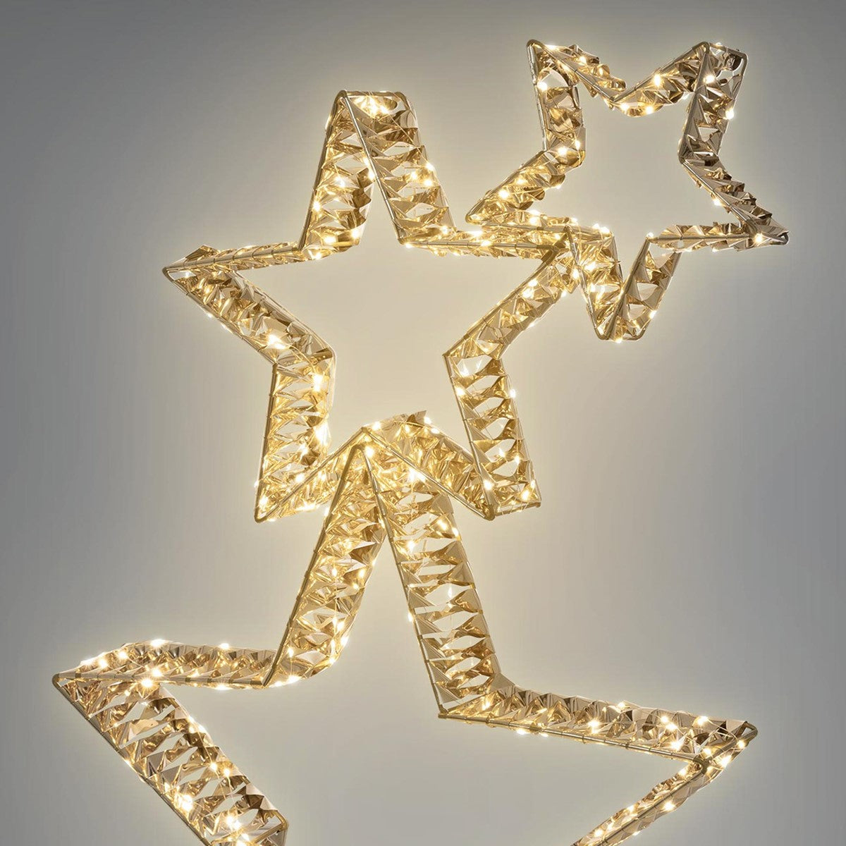 Estrelas douradas com luzes sobre um fundo cinzento.