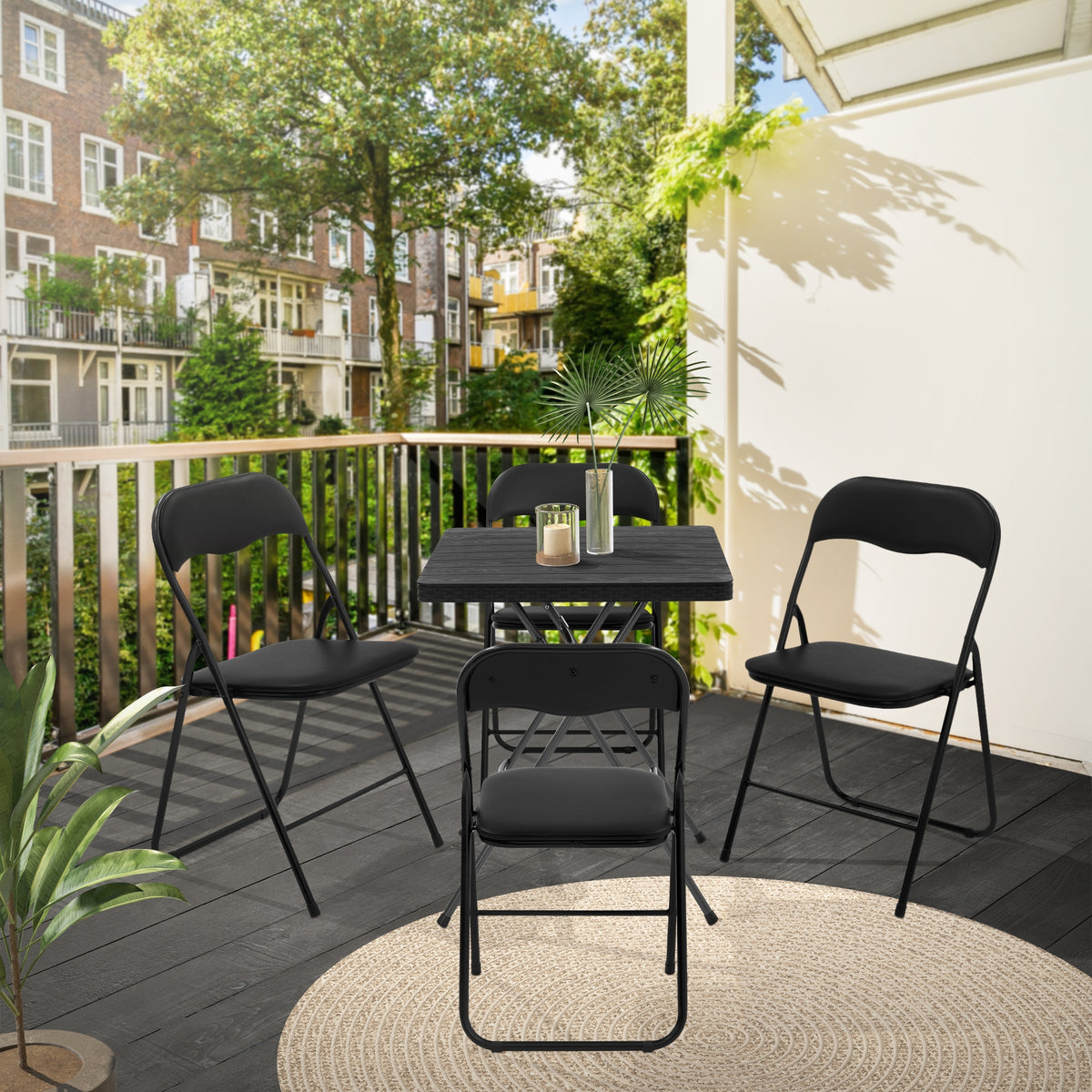 Sort klapstol og bord på en terrasse med planter.