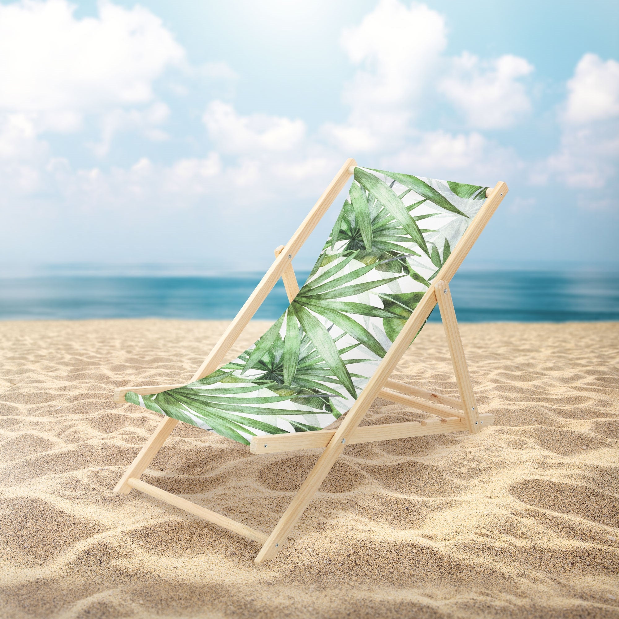 Liegestuhl am Strand mit Palmenmuster und Meer im Hintergrund.