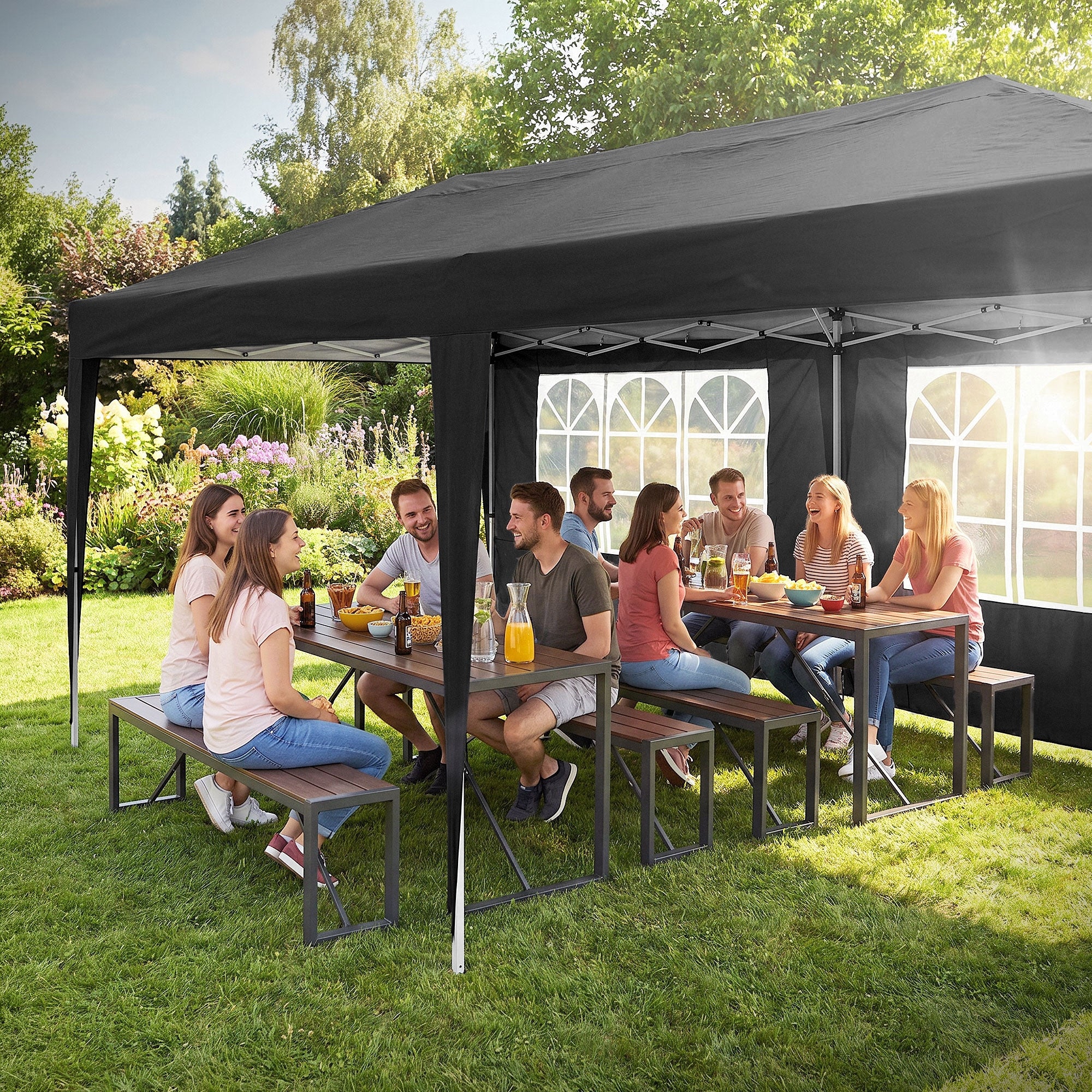 Groupe de personnes assises à une table sous un pavillon dans le jardin.