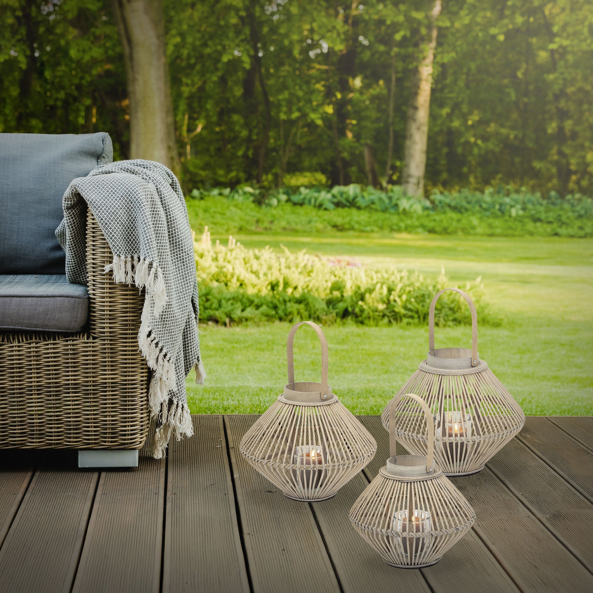 Terrasse mit Rattan-Sofa, Decke und Bambuslaternen im Garten.