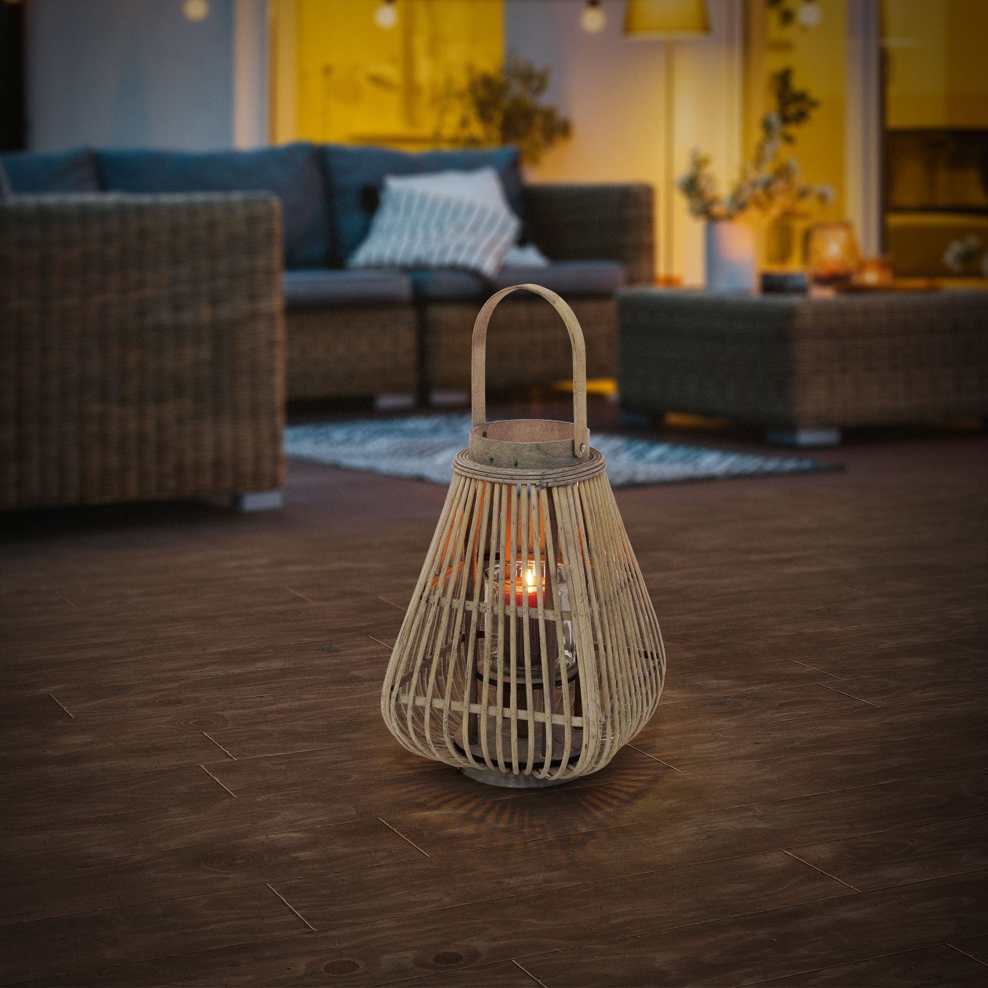 Bamboo lantern on a wooden floor, illuminated, with furniture in the background.