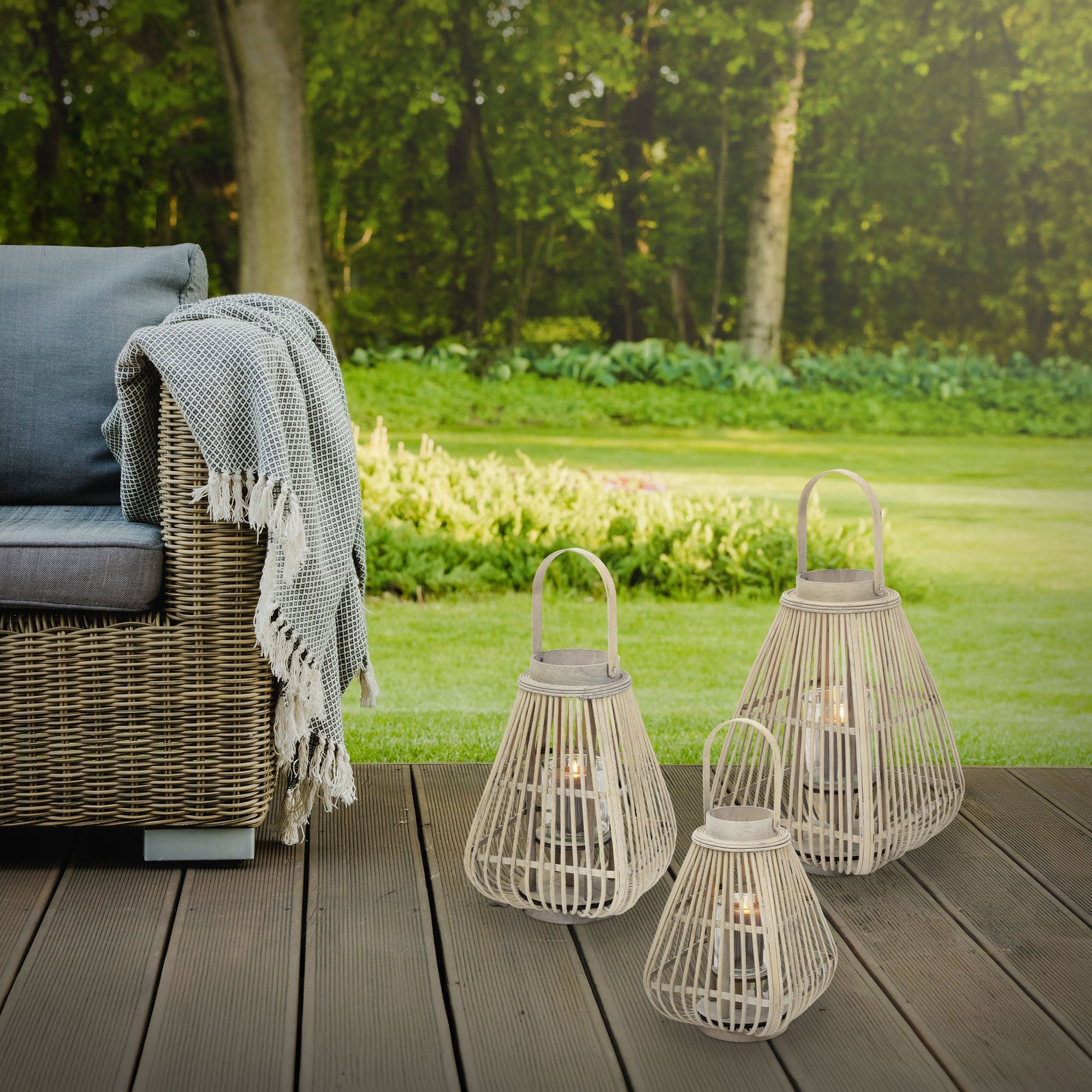 Three lanterns on a terrace, surrounded by greenery and a sofa.