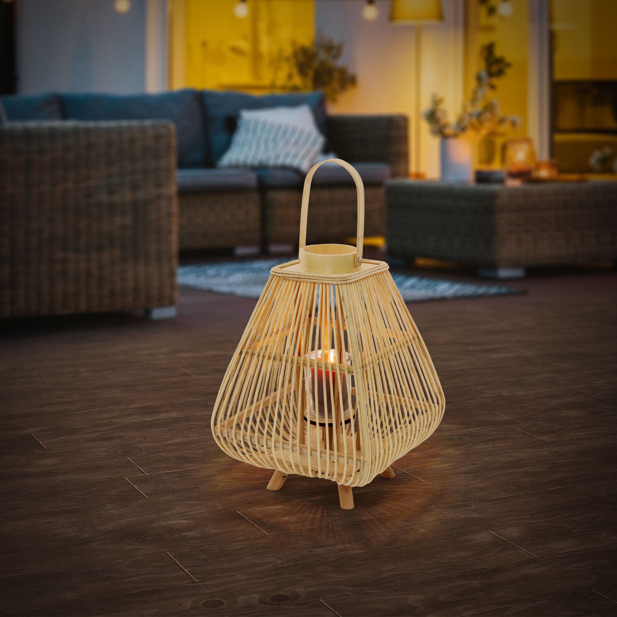 A lantern is standing on a dark floor in a cozy room with sofas.