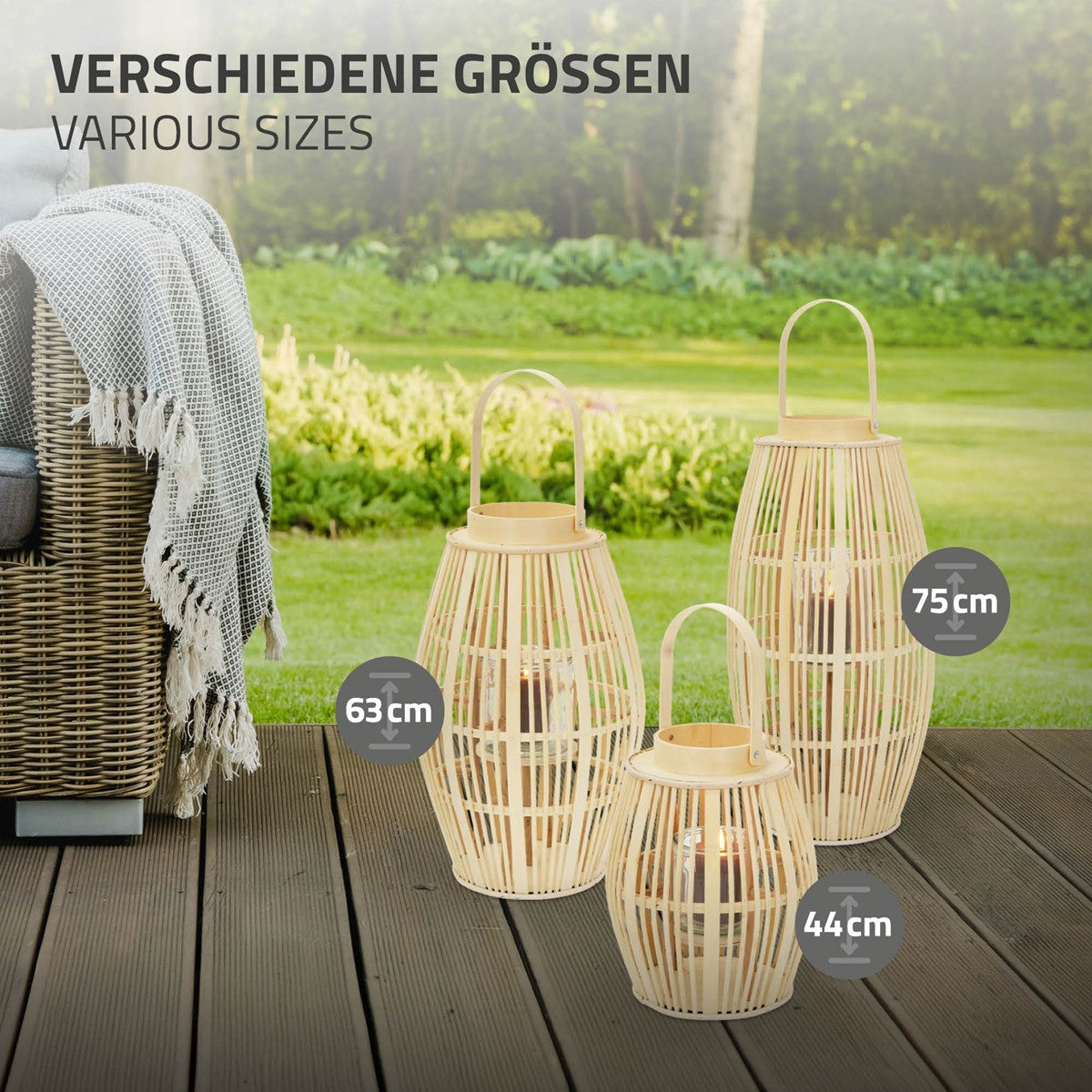 Three lanterns of different sizes stand on a wooden floor in the garden.