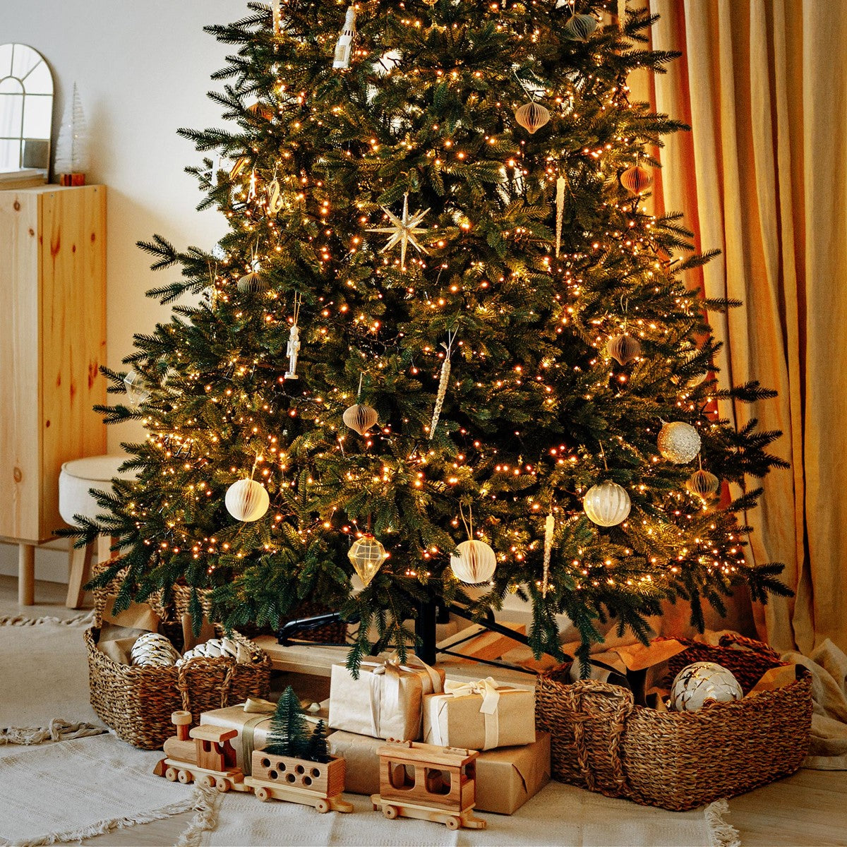 Geschmückter Weihnachtsbaum mit warmweißer Beleuchtung, Kugeln und Geschenken darunter.