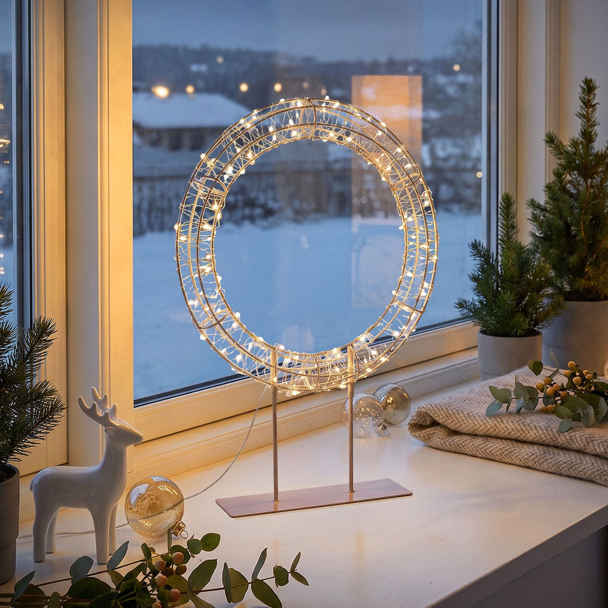 Een verlichte decoratie in de vorm van een ring voor een raam met sneeuw.