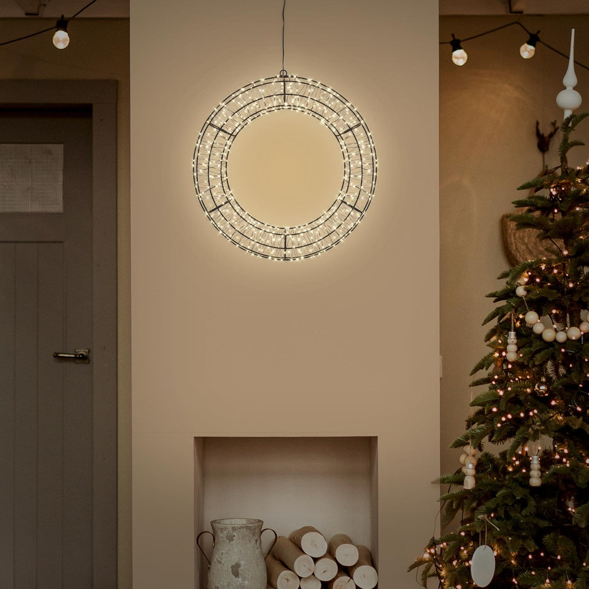 Lichtkranz hängt an einer Wand über einem Weihnachtsbaum in einem gemütlichen Raum.