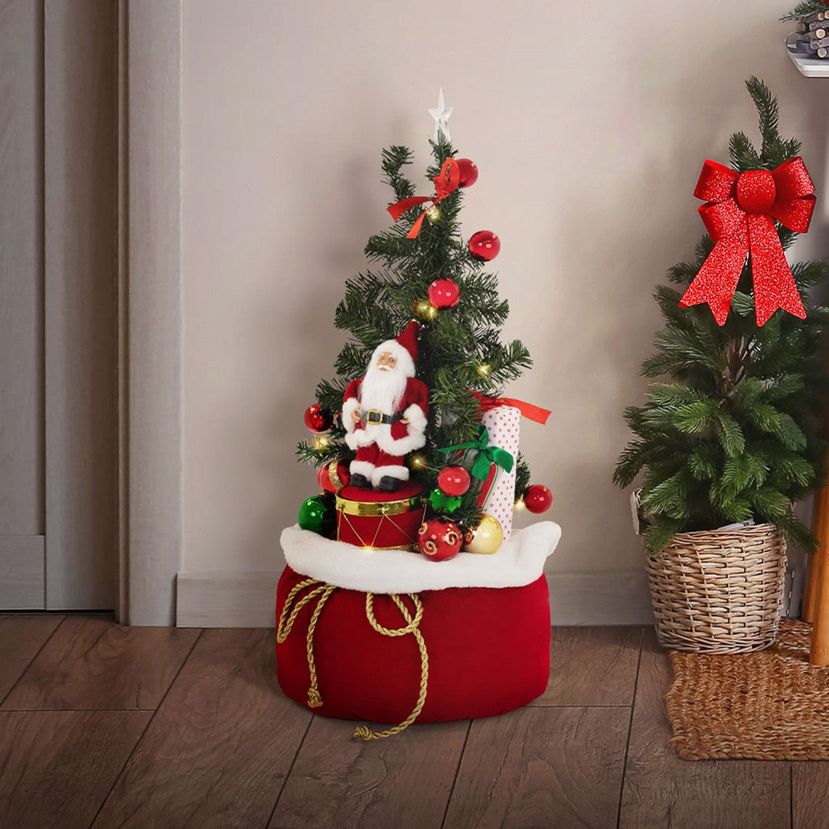 Kleiner Weihnachtsbaum mit Weihnachtsmann-Figur und Geschenken auf einem roten Sockel.