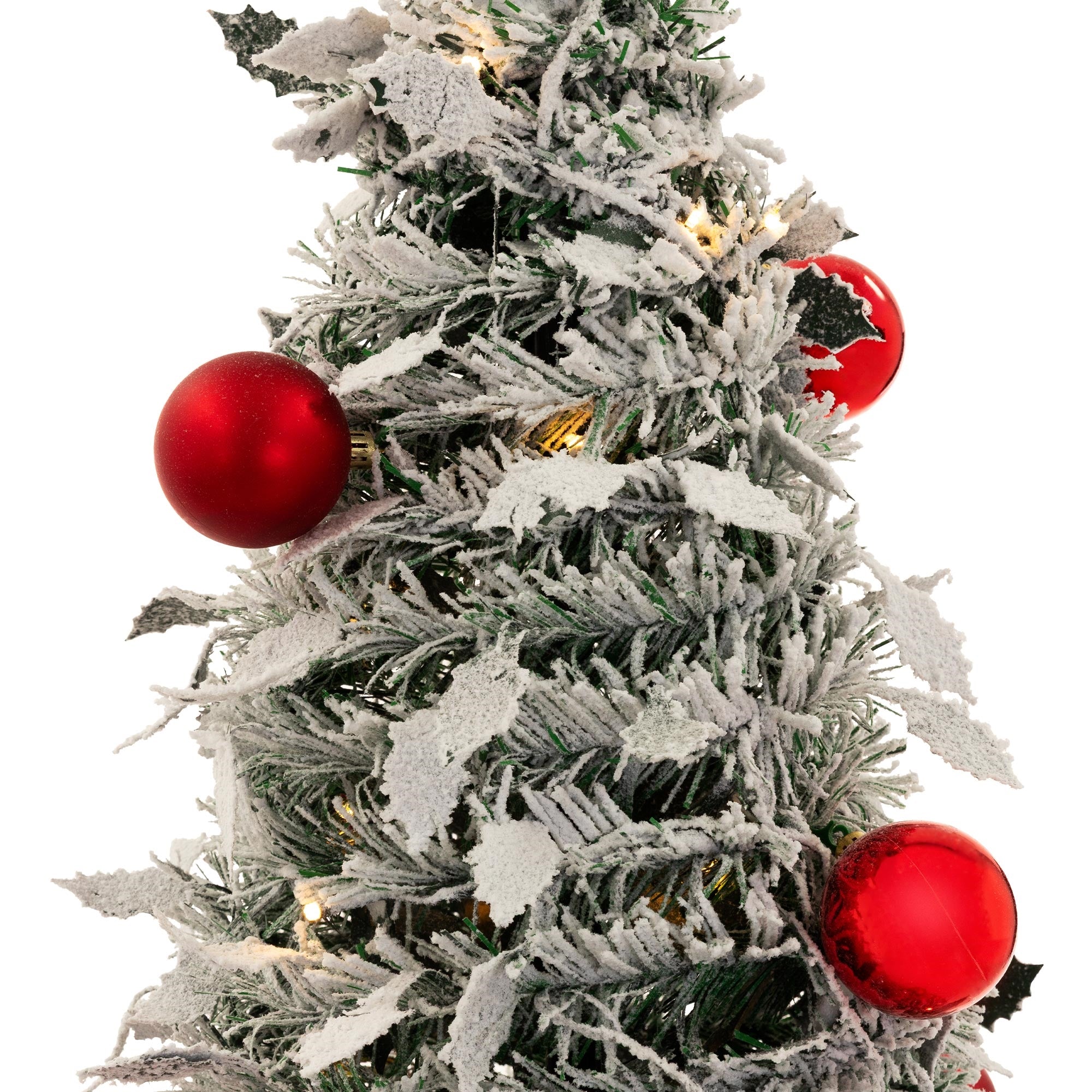 Nahaufnahme eines künstlichen Weihnachtsbaums mit roten Kugeln und schneebedeckten Zweigen.