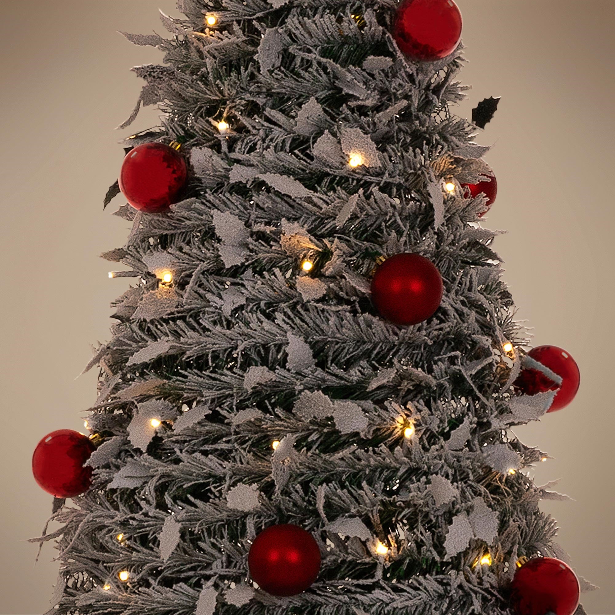 Nahaufnahme eines künstlichen Weihnachtsbaums mit roten Kugeln und Lichtern.