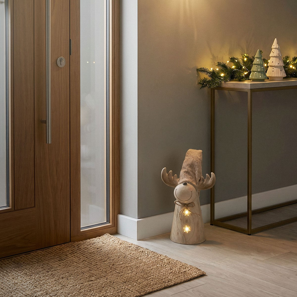 Eingangsbereich mit Holzhaustür, Teppich und dekorativen Weihnachtsfiguren.