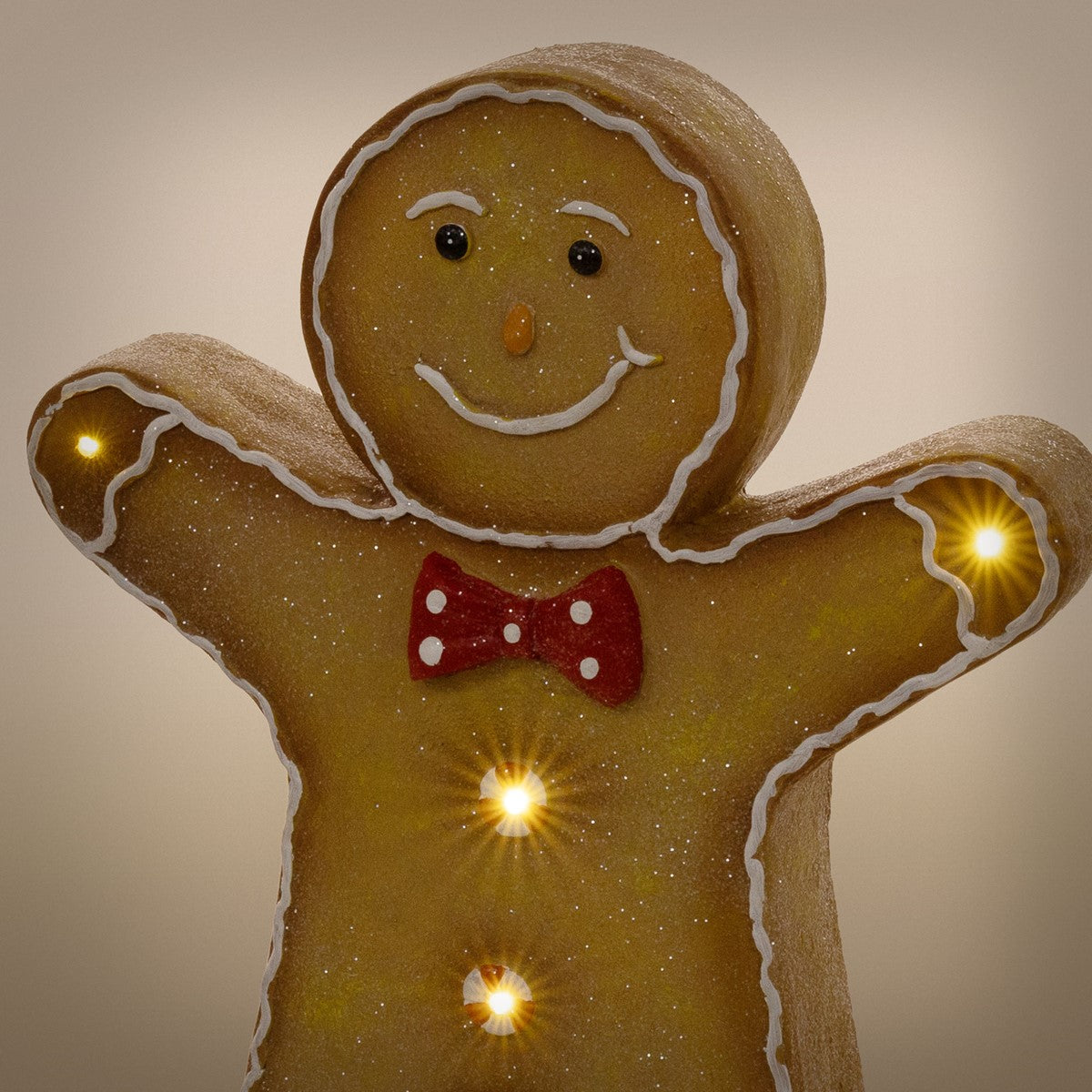 Lebkuchenfigur mit roter Fliege und leuchtenden Knöpfen, vor neutralem Hintergrund.