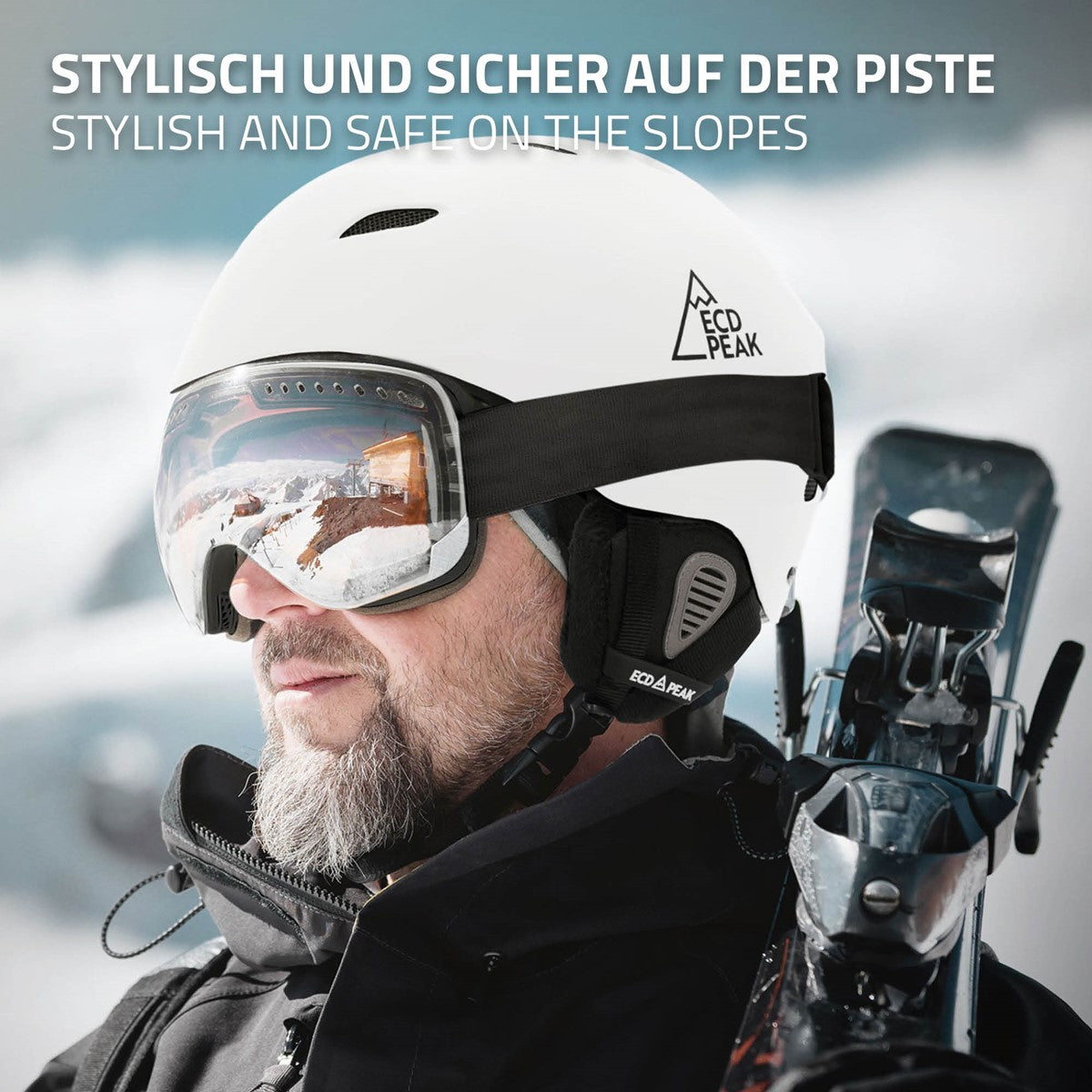Mann mit weißem Skihelm und Skibrille, im Hintergrund schneebedeckte Berge.