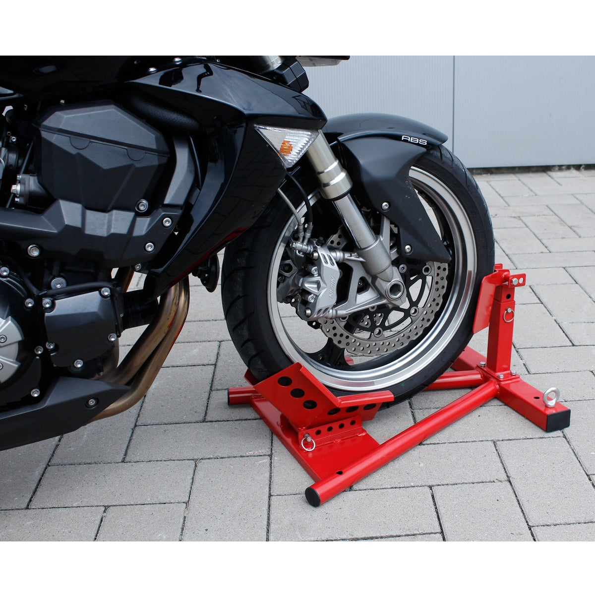 Ein roter Motorradständer, der ein Motorrad mit einem schwarzen Rahmen stützt.