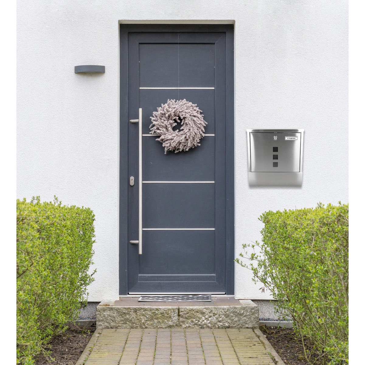 Haustür mit Kranz und silbernem Briefkasten.