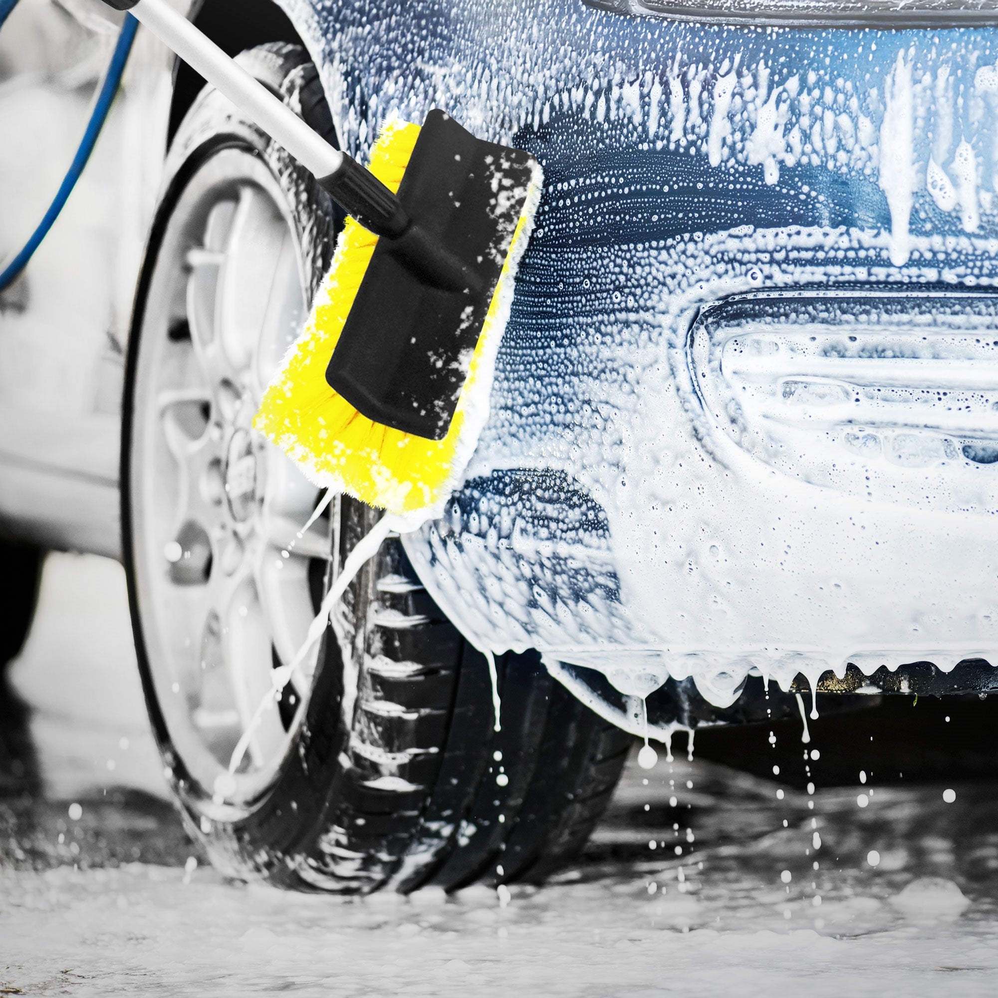 Ein Auto wird mit einem gelben Schwamm gewaschen, Schaum und Wasser sind sichtbar.