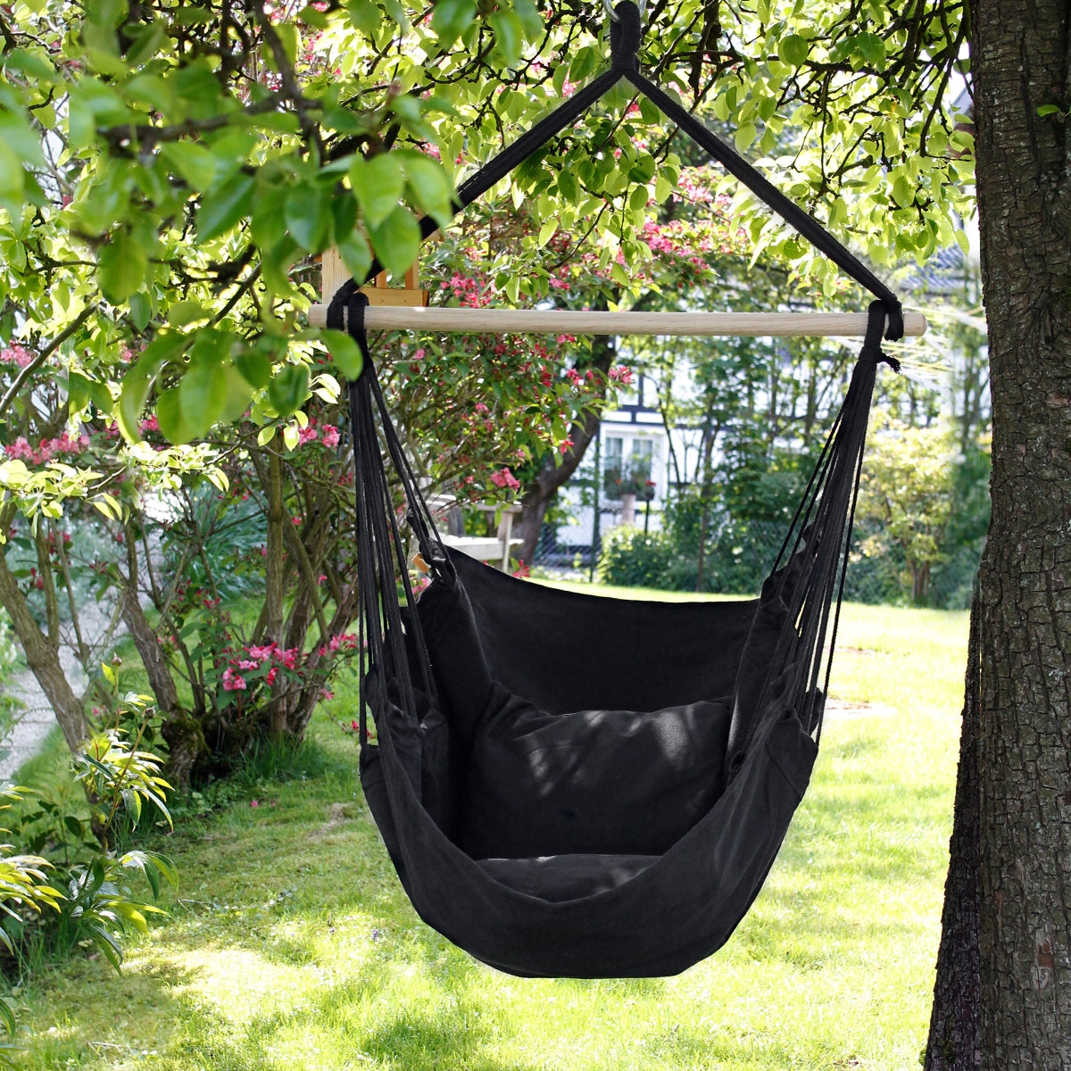 Schwarzer Hängesessel, hängend unter einem Baum in einem Garten.