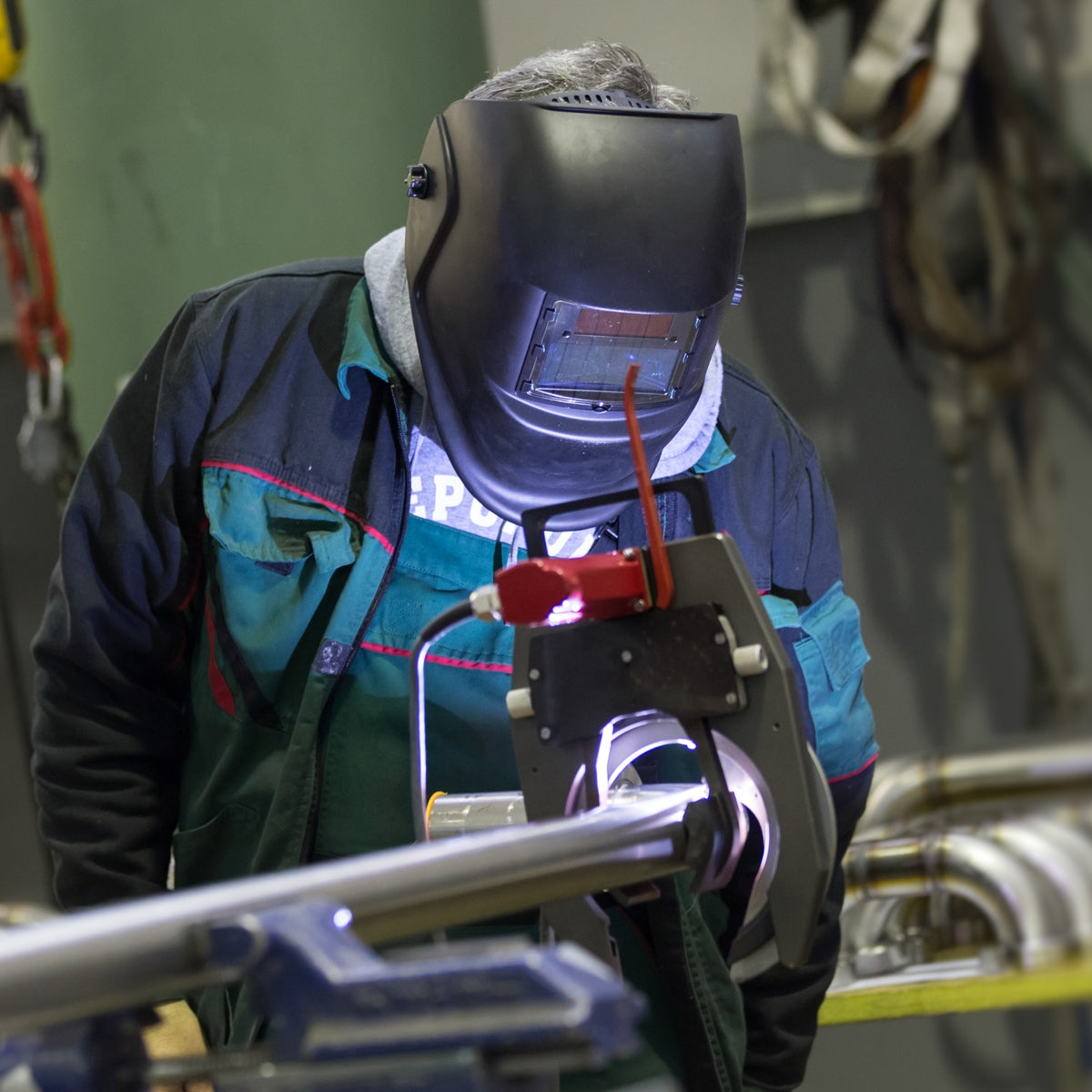 A man in work clothes welding with a welding machine.
