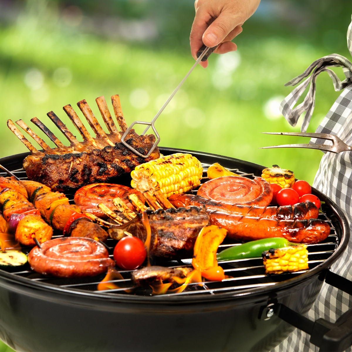 Grill mit verschiedenen Fleischsorten und Gemüse im Freien.