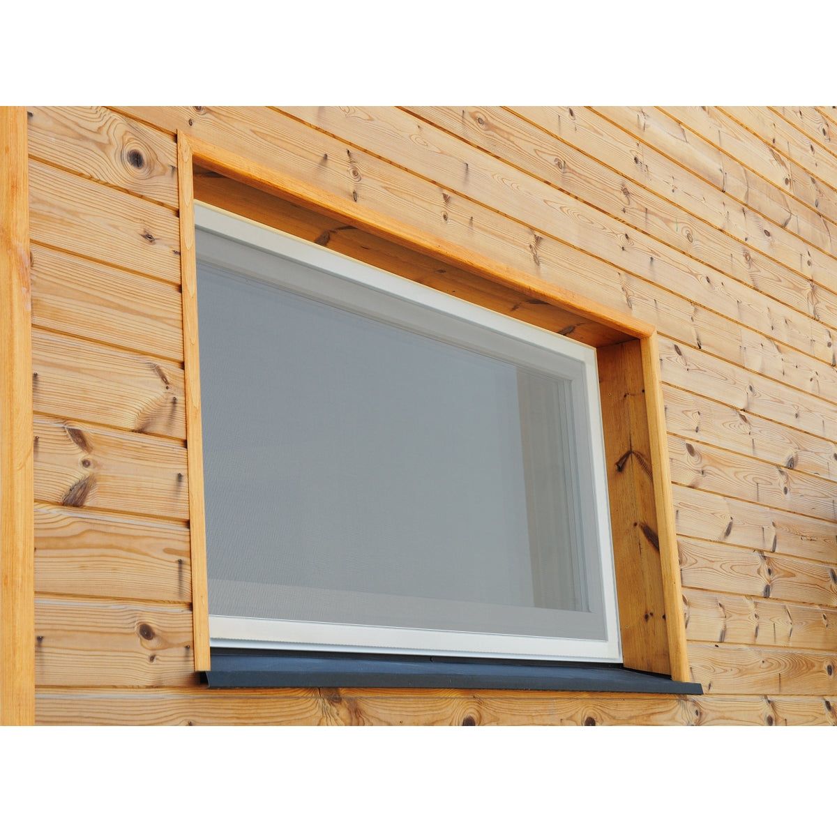 Ein Fenster mit grauem Insektenschutzgitter in einer Holzverkleidung.