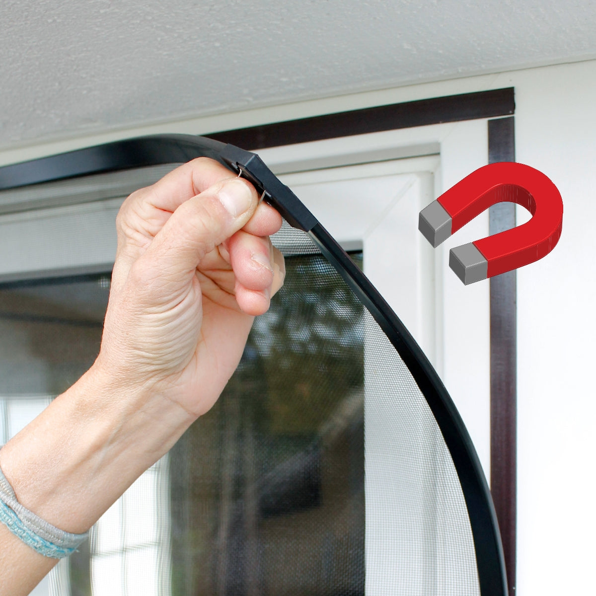 Eine Hand hält einen flexiblen Rahmen mit einem Magneten an einem Fenster.