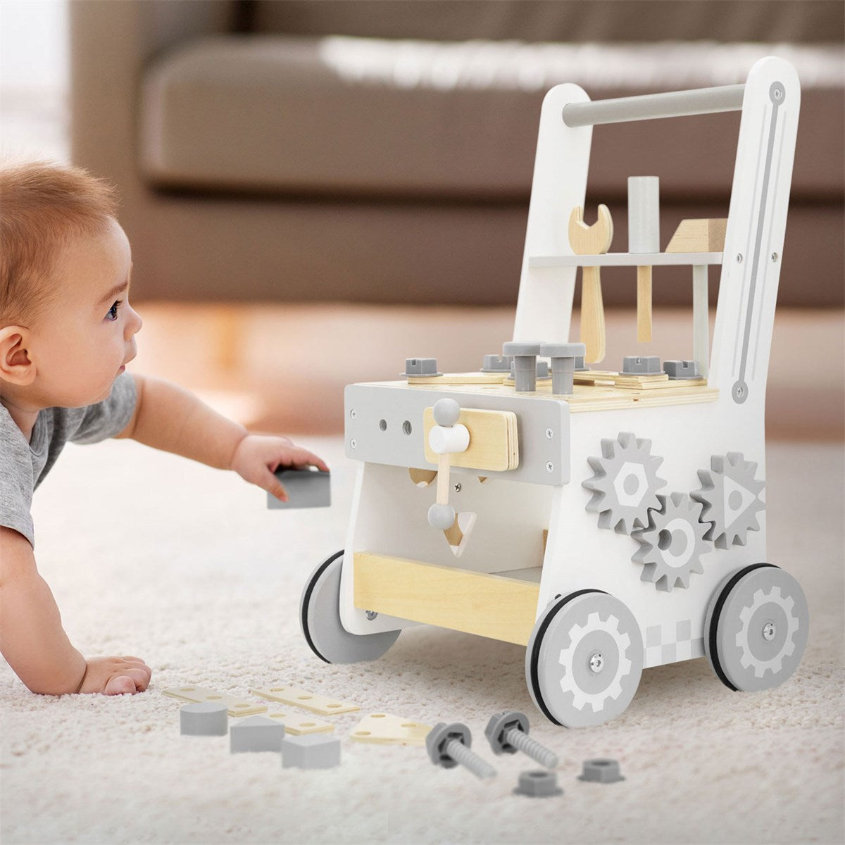 Ein Kleinkind spielt mit einem Holzspielzeugwagen auf einem Teppich.