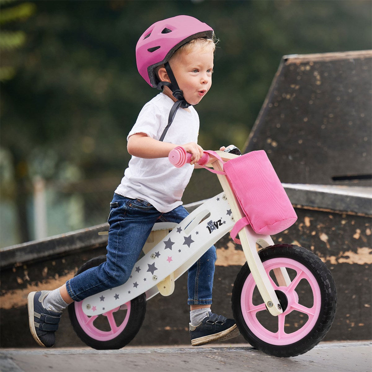 Ein Kind fährt auf einem Kinderfahrrad mit Helm in einem Skatepark.