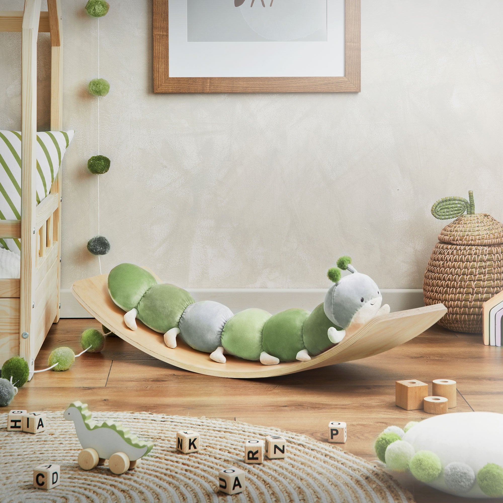 Planche d'équilibre avec un jouet chenille en peluche verte. Blocs de jouets au premier plan.