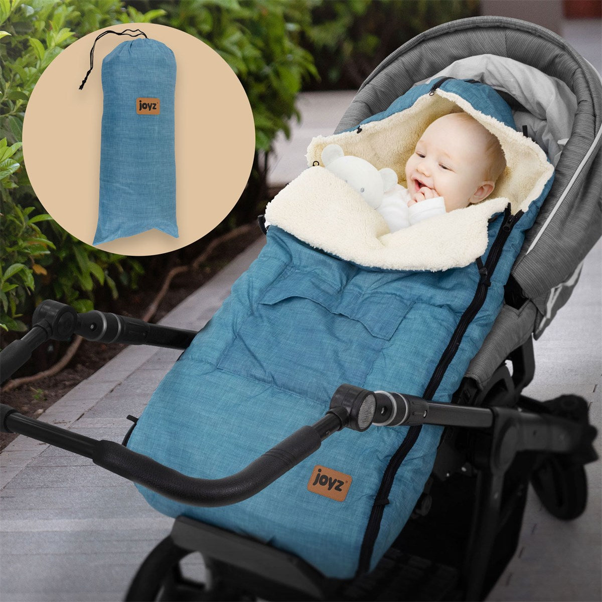 Baby in blauer Decke im Kinderwagen, mit einem Spielzeug.