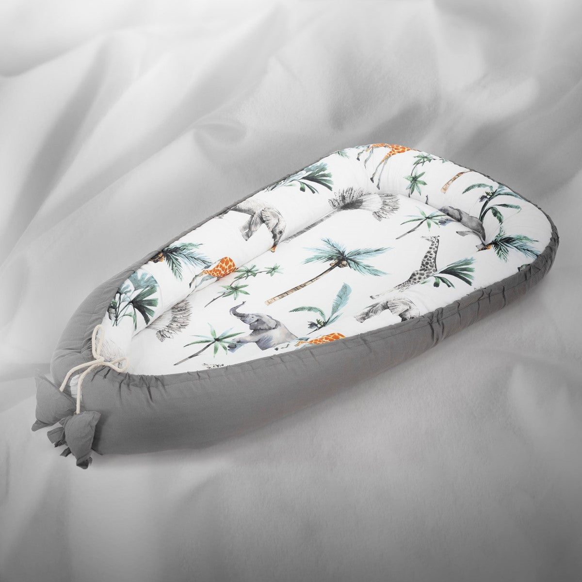 Ein Baby Nest mit Tiermotiven und Palmen auf einem grauen Hintergrund.
