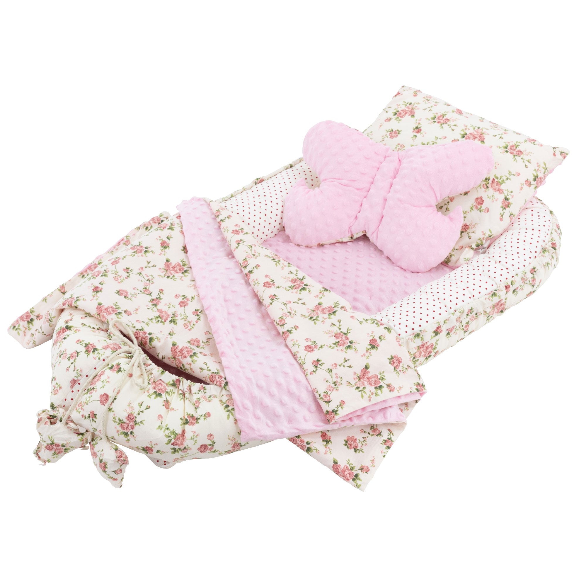 Nid pour bébé avec coussin et couverture roses, motif floral et coussin en forme de papillon.
