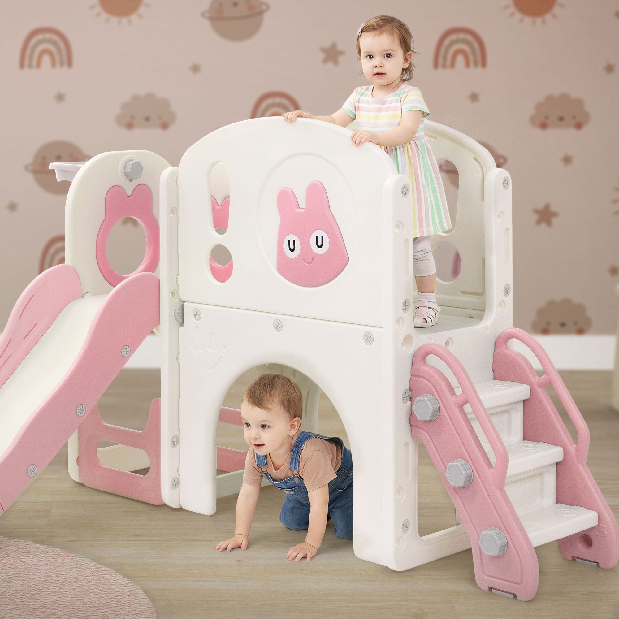 Zwei Kinder spielen auf einem Spielturm mit Rutsche und Kletterelement.