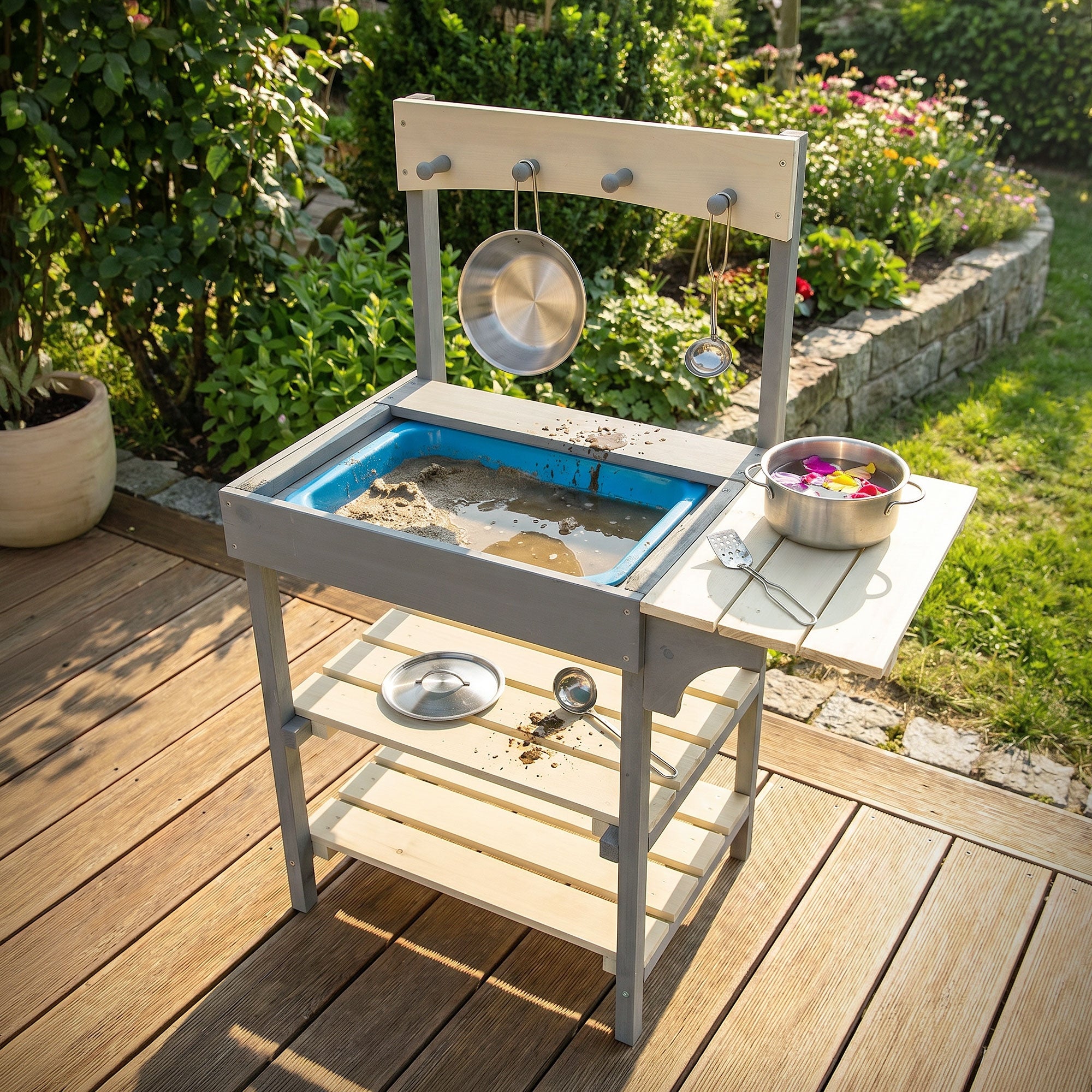 Matschküche mit Sand und Spielzeug auf einer Terrasse.