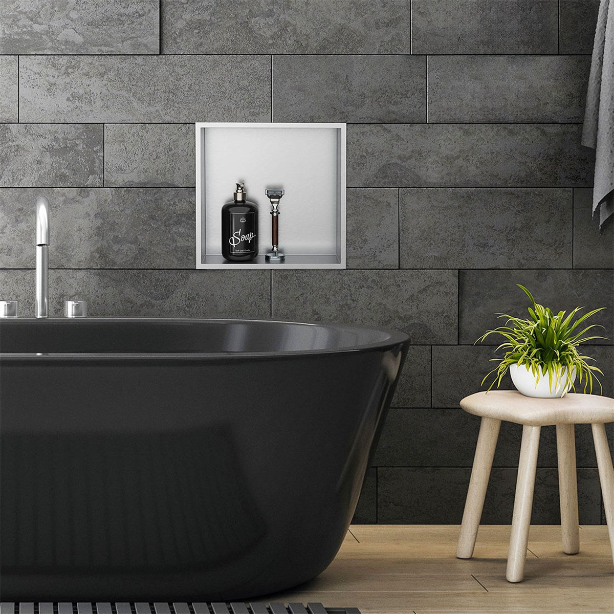 Black bathtub in front of a gray wall with a niche and plants.