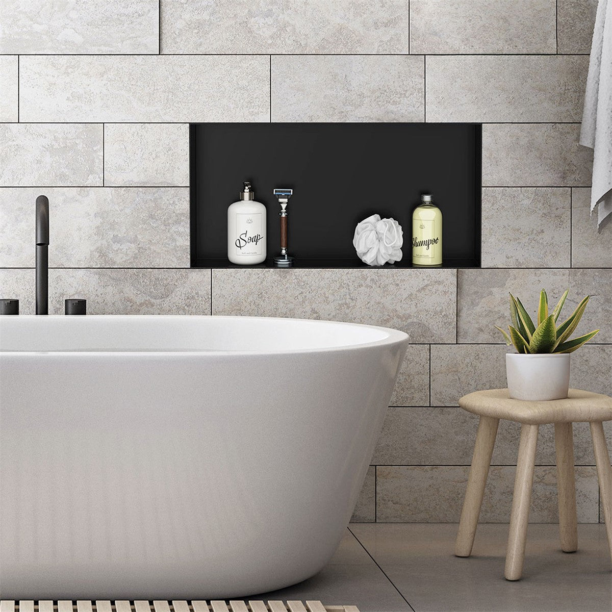 Freestanding bathtub in front of a stone wall with a shelf in the background.