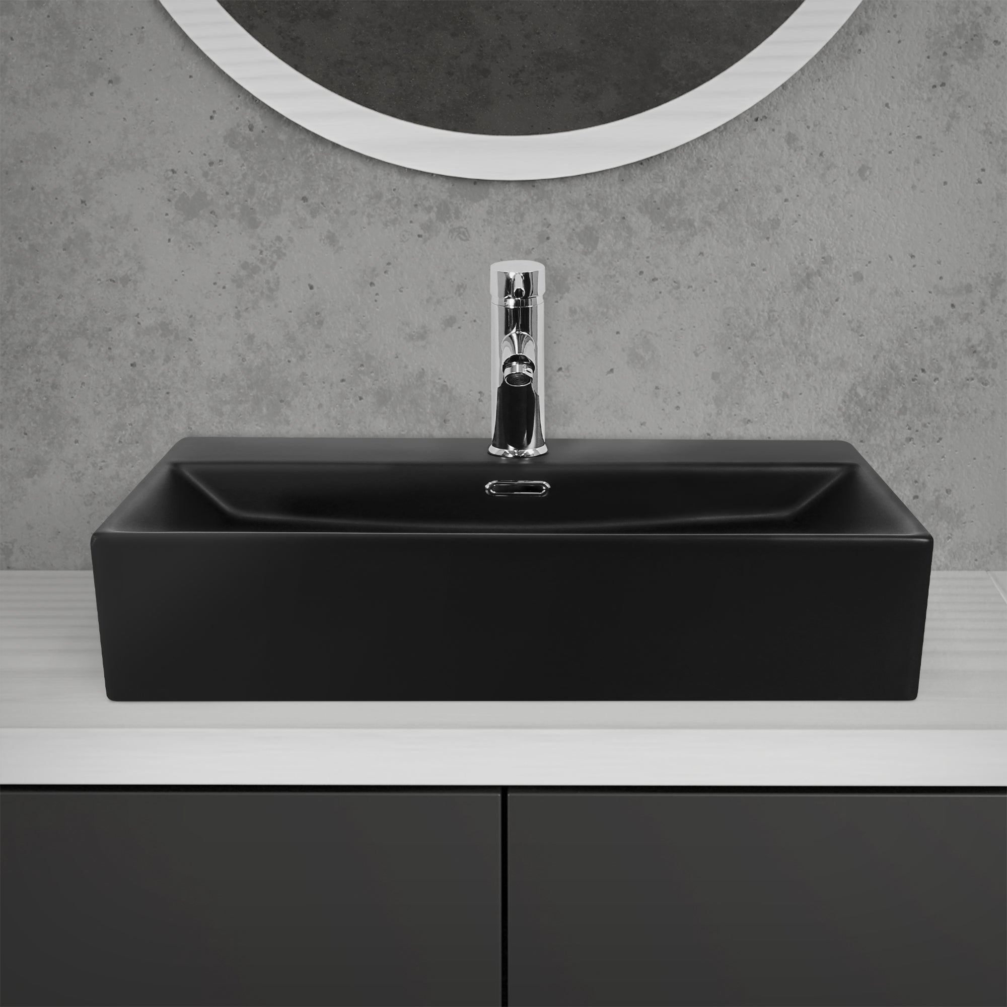 Schwarzes Waschbecken mit glänzendem Wasserhahn auf einer weißen Oberfläche.