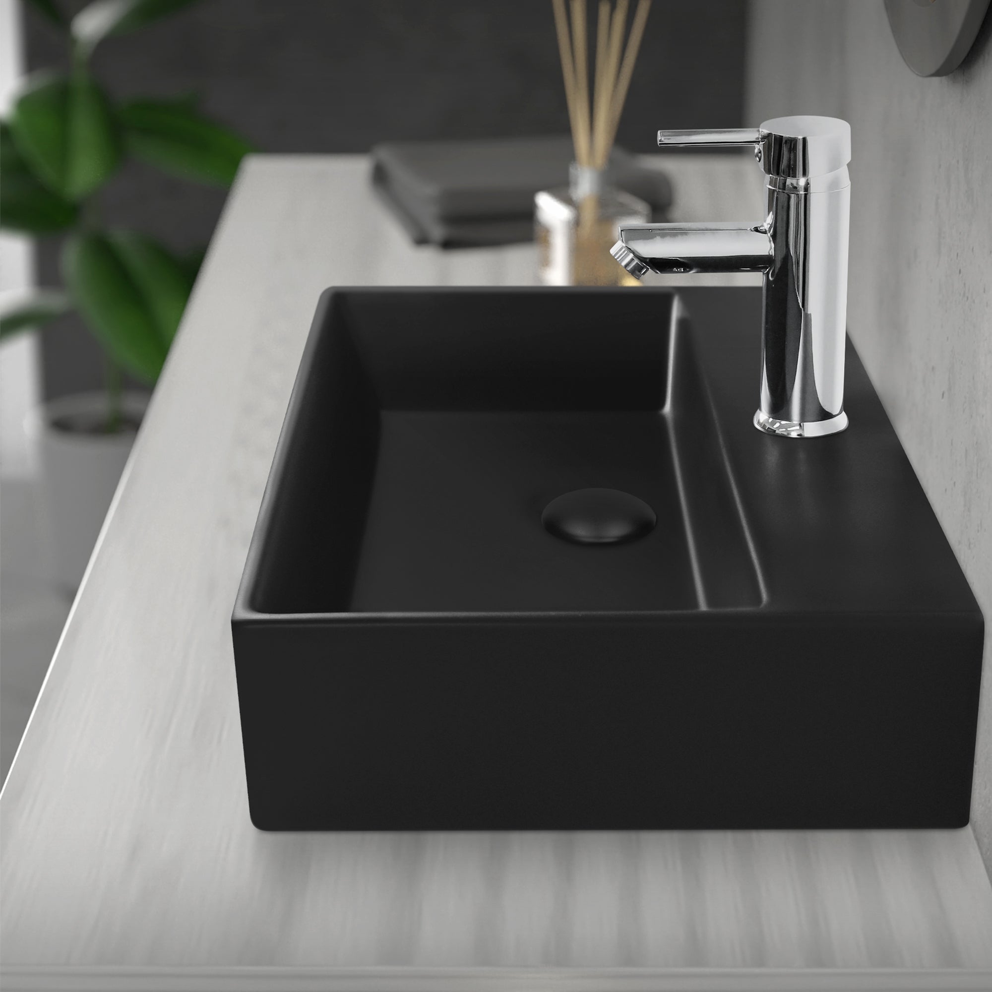 Schwarzes Waschbecken mit modernem Wasserhahn auf einem Tisch.