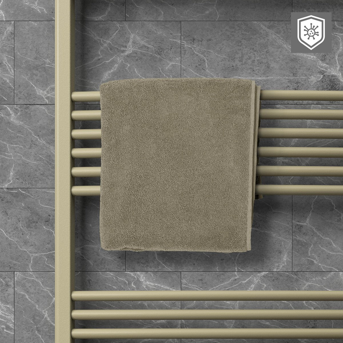 Een beige handdoek hangt over de dwarsstangen van een beige handdoekradiator voor een grijze betegelde muur.