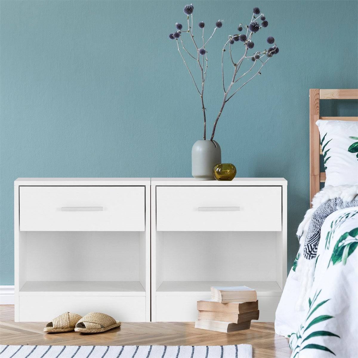 Two white bedside tables with open compartments and a vase.