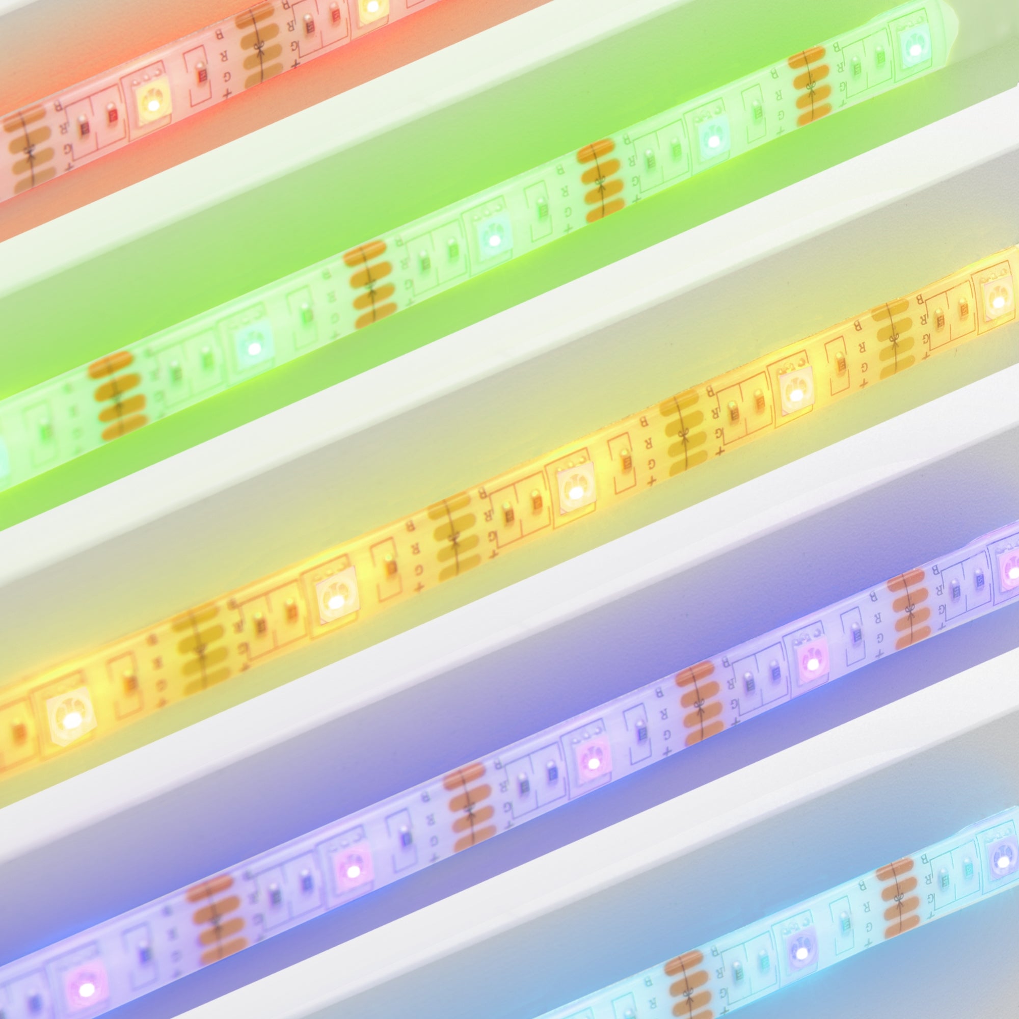 Bandes LED colorées de différentes couleurs sur une surface blanche.