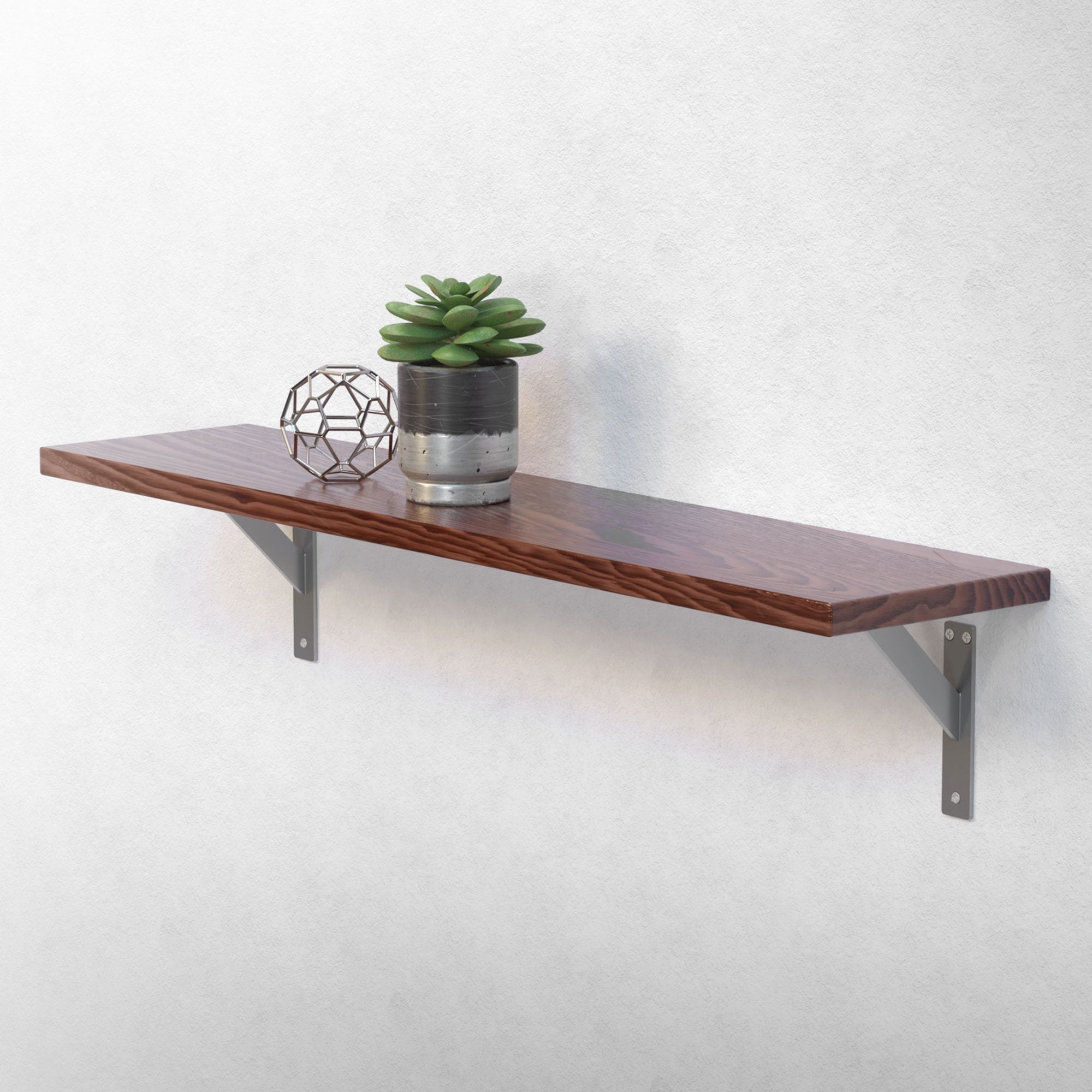 Houten plank met plant en decoratie aan een witte muur.