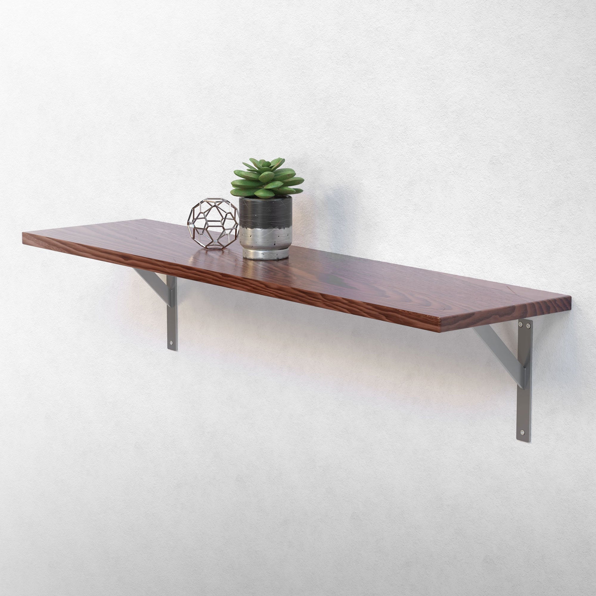 Houten plank met plant en decoratieve bal aan een muur gemonteerd.