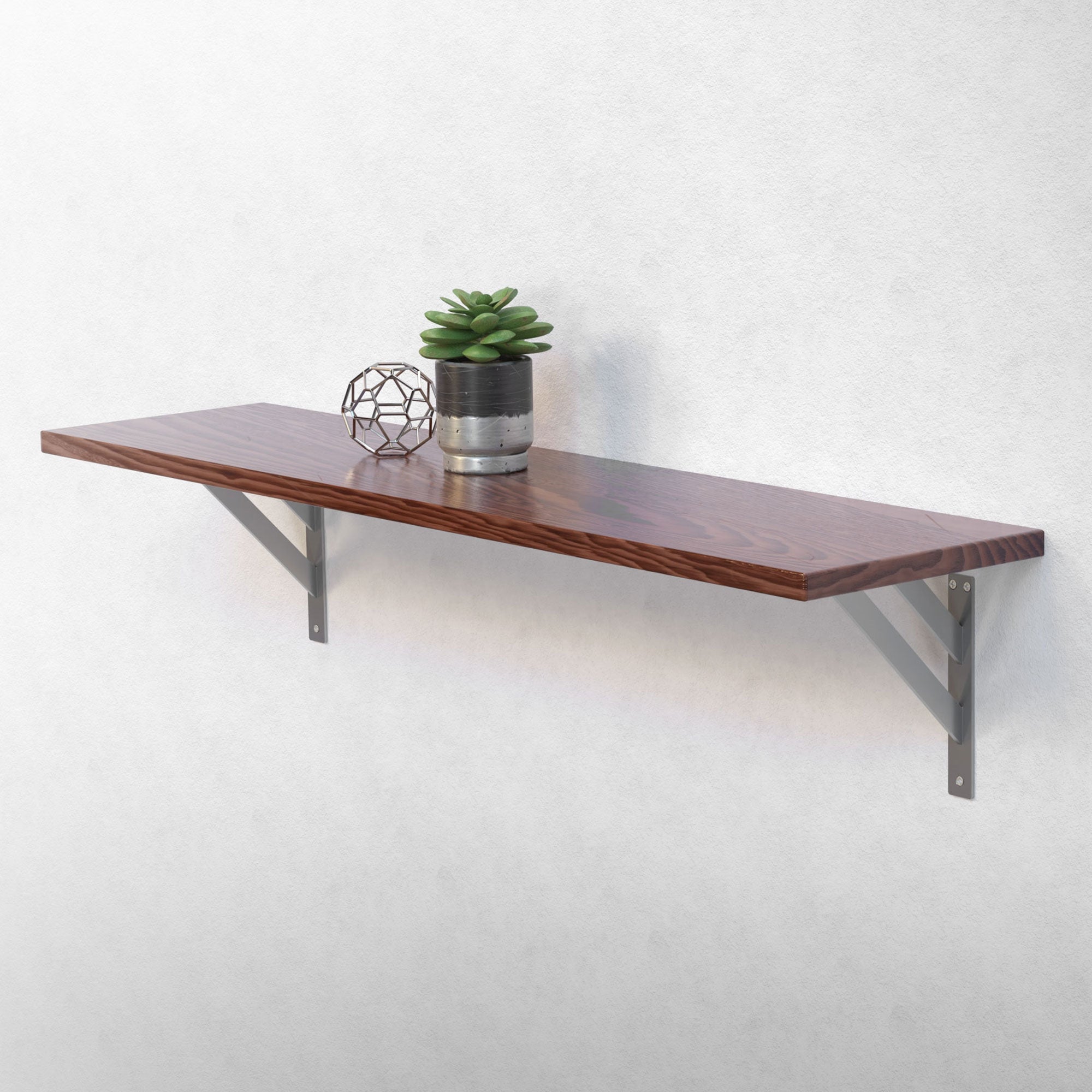 Houten plank op wandbeugels met plant en decoratie.
