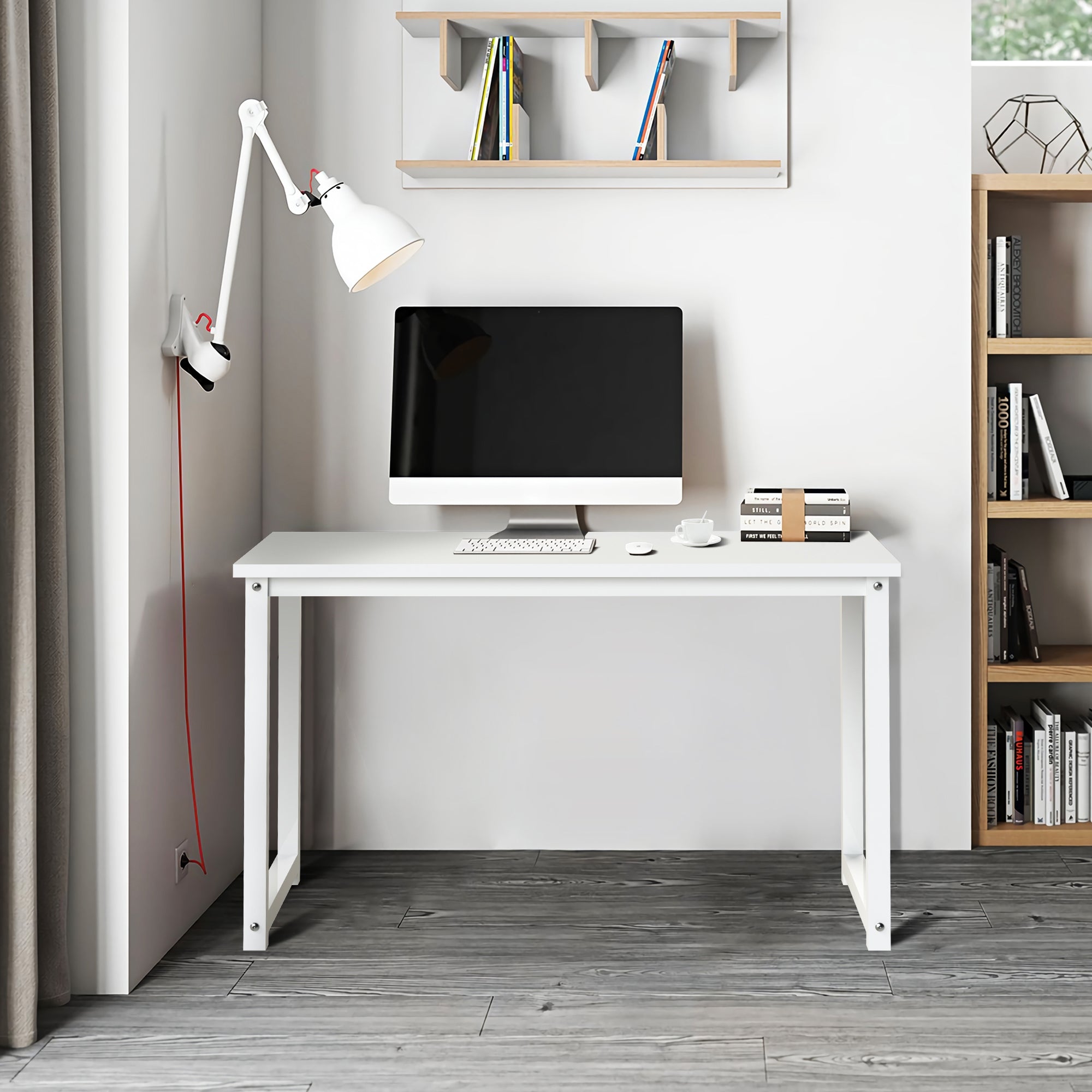 Ein moderner Schreibtisch mit Computer, Lampe und Bücherregal an einer Wand.