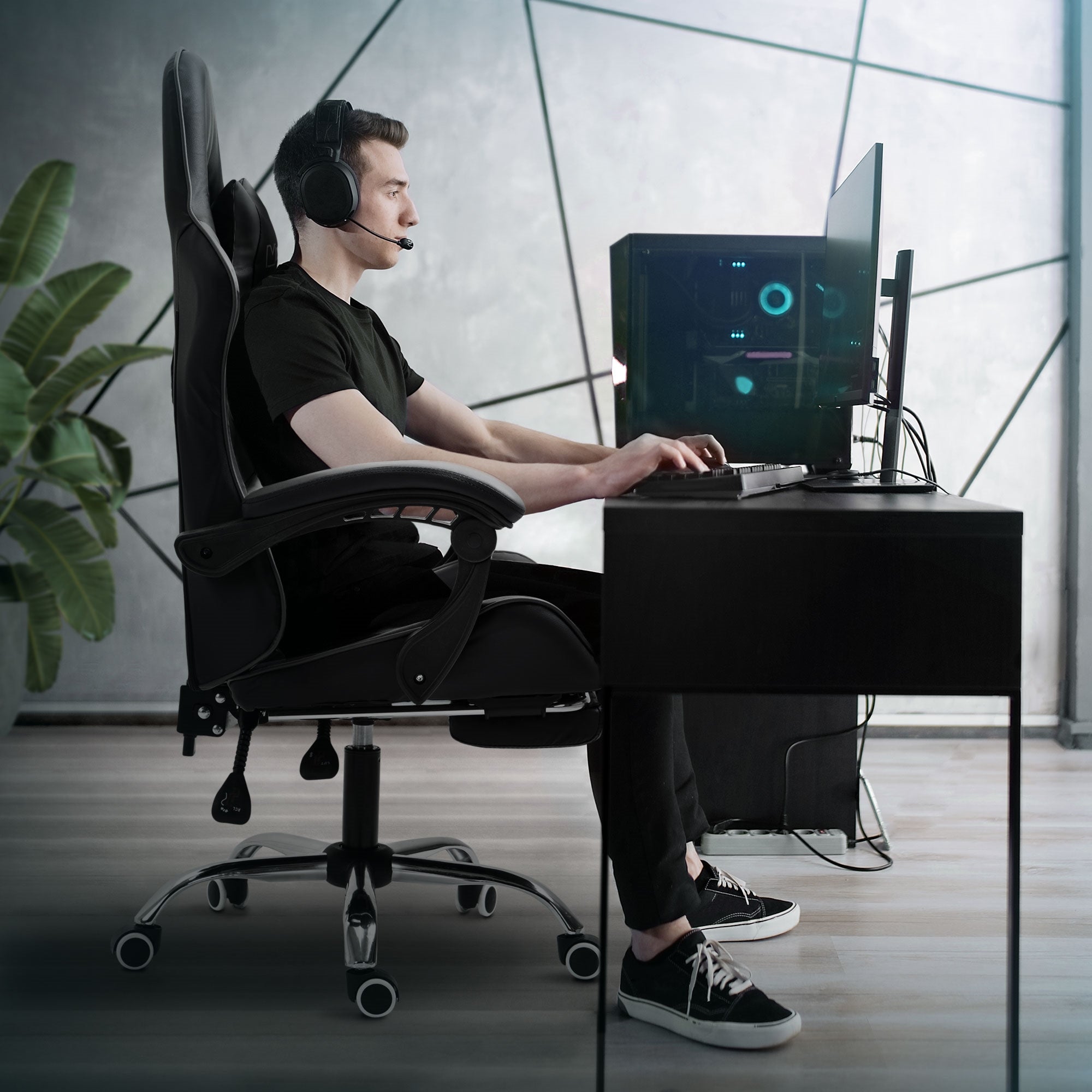 Mann sitzt an einem Schreibtisch in einem Gaming-Stuhl und trägt Kopfhörer.