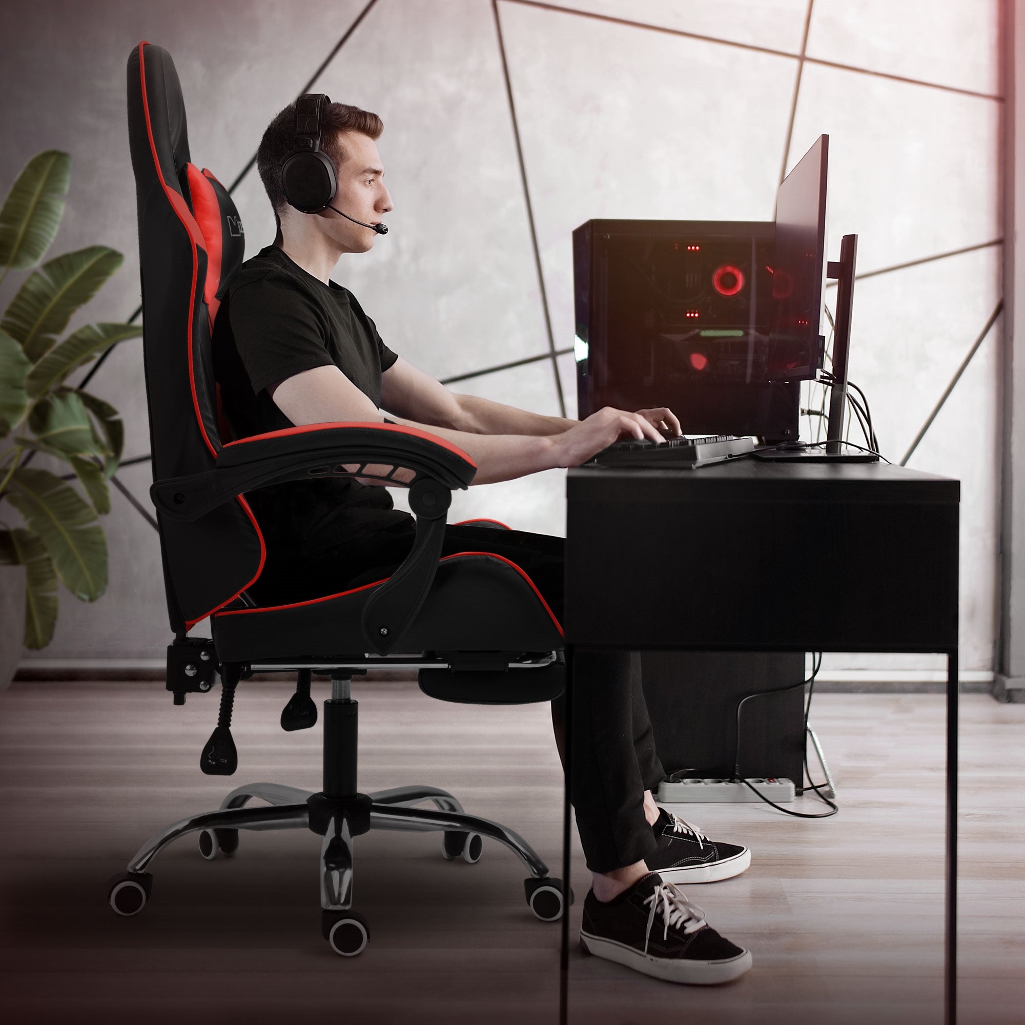Young man sitting at a desk in a gaming chair wearing headphones.