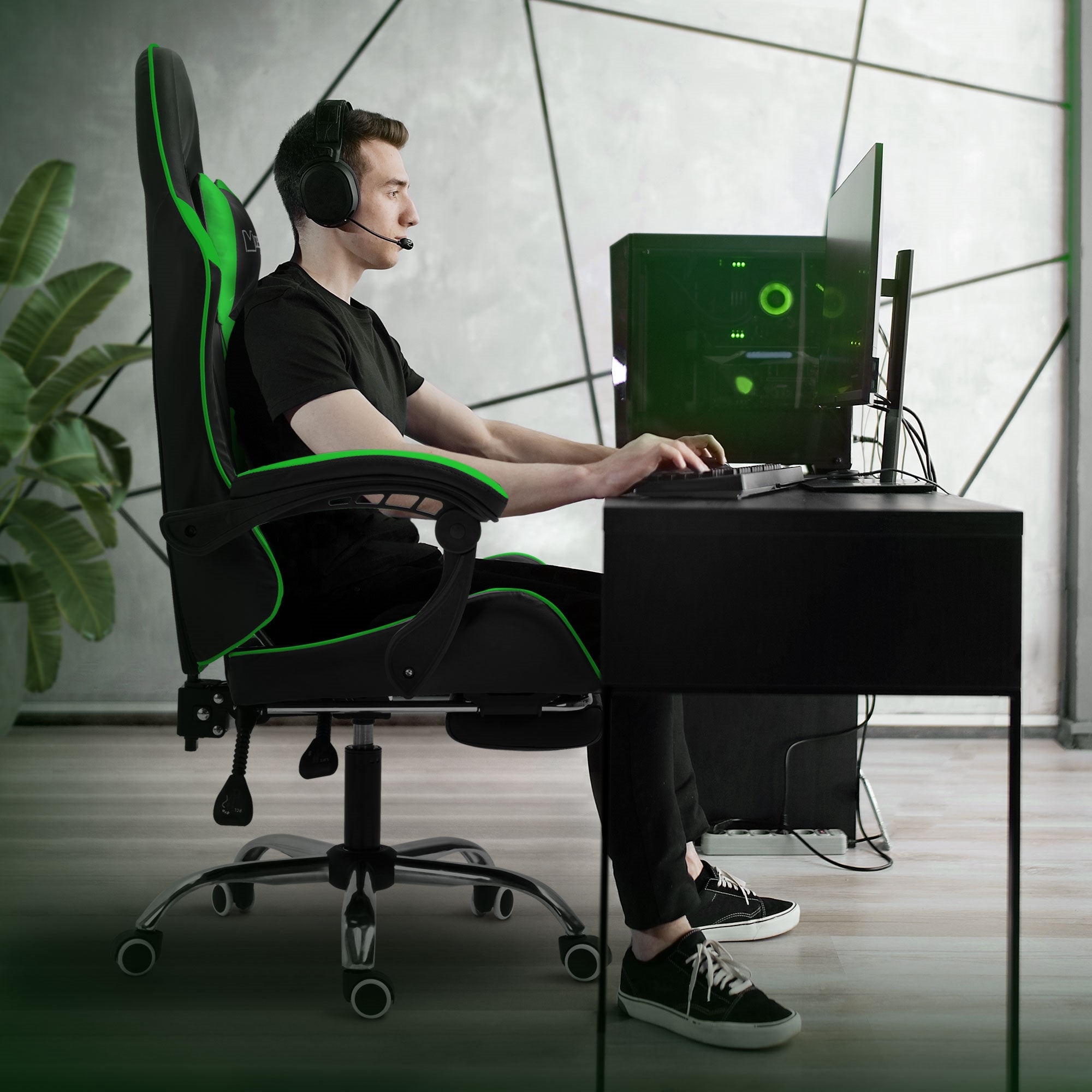 Jeune homme assis à un bureau dans une chaise de gaming en train de jouer sur l'ordinateur.